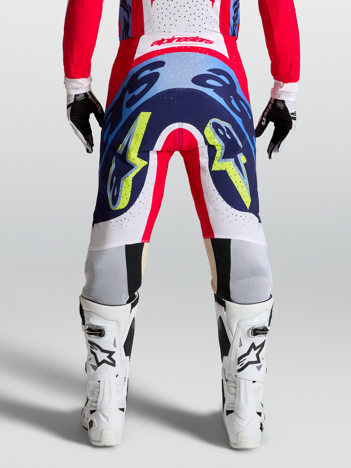 Alpinestars Pantalon Supertech Dyna, pantalon de motocross pour course, bleu marine et rouge, construction rip-stop extensible, vue de dos sur mannequin avec bottes
