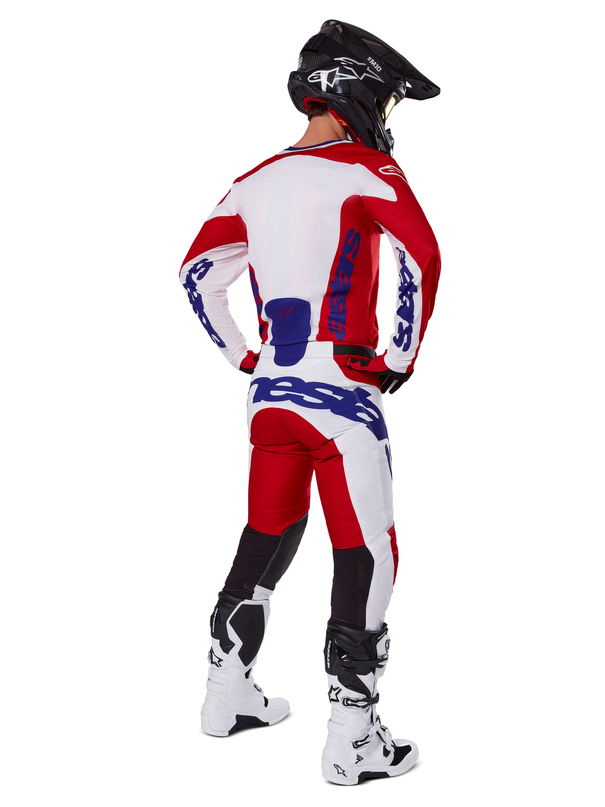 Alpinestars 2025 Racer Veil Pants, pantalon de motocross, rouge vif et blanc avec accents bleus, vu de dos sur un pilote en tenue complète, avec marquage Alpinestars audacieux, empiècements respirants sur le bas des jambes, bottes blanches et casque noir coordonnés.