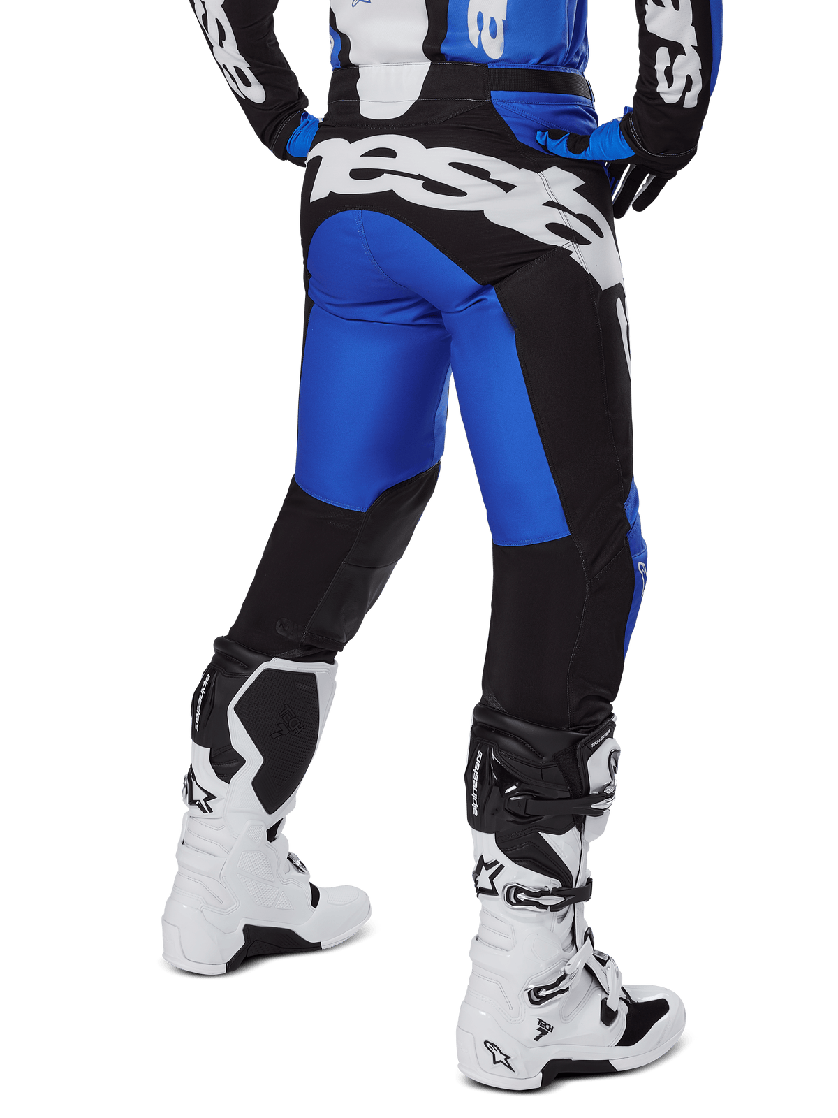 Pantalon Alpinestars Racer Veil 2025, pantalon de motocross, bleu et noir, vue arrière montrant un grand logo blanc sur l'assise, porté avec le maillot assorti et des bottes blanches, matériau technique durable pour la conduite tout-terrain