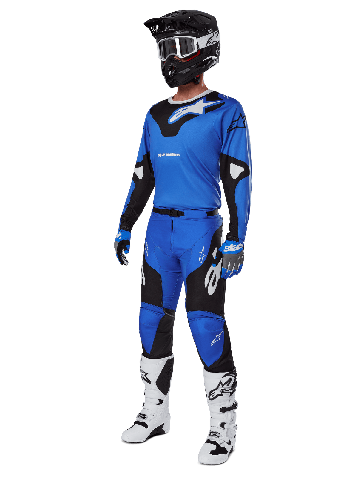 Pilote de motocross portant un équipement de course complet, comprenant le pantalon Alpinestars 2025 Racer Veil bleu et noir, un maillot bleu assorti avec des accents blancs, un casque noir avec des lunettes blanches, des bottes blanches et noires et des gants bleus, tenue coordonnée pour la course tout-terrain