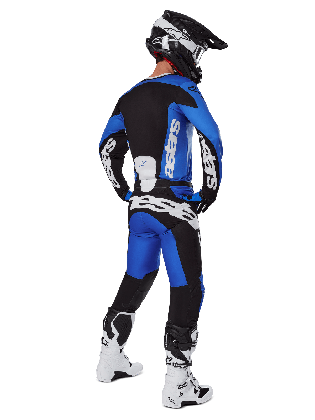 Pilote de motocross vu de dos portant le pantalon Alpinestars 2025 Racer Veil bleu et noir, maillot à manches longues assorti avec logo blanc, bottes Tech 7 blanches et noires, et casque SM10 noir, tenue de course tout-terrain complète
