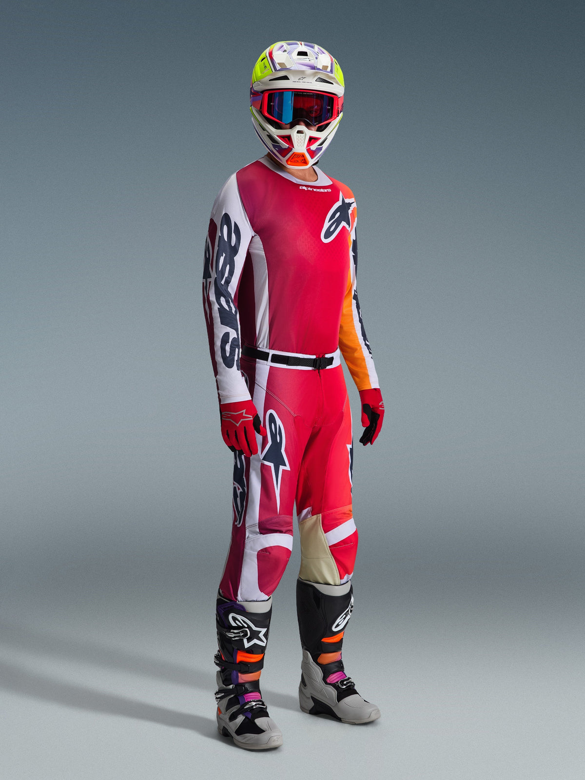 Pantalon Alpinestars Racer Portl 2026, pantalon de motocross, rouge, gris clair et gris foncé, porté dans le cadre d'une tenue de course complète avec maillot assorti, gants rouges, casque coloré avec lunettes bleues et bottes grises, construction durable pour la performance en motocross tout-terrain