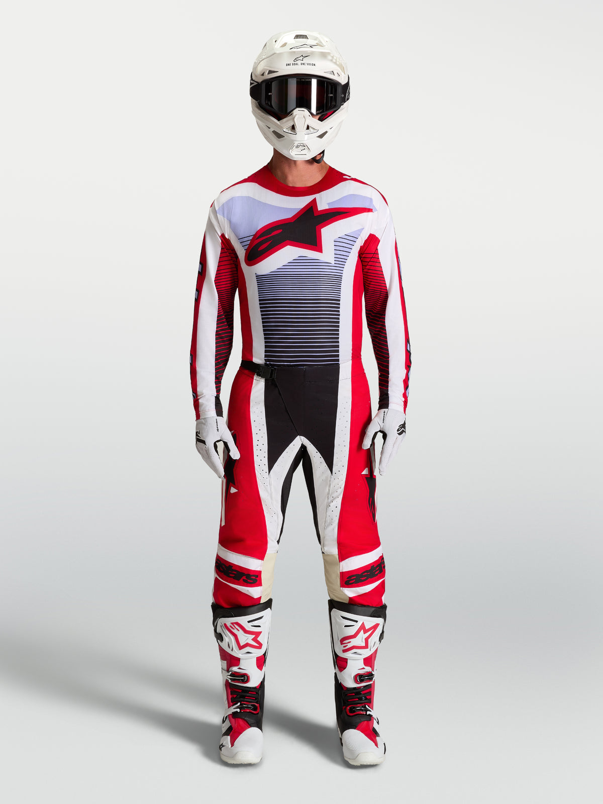 Pantalon Techstar Maven Alpinestars, équipement de motocross rouge et blanc avec détails lavande, porté avec bottes et casque