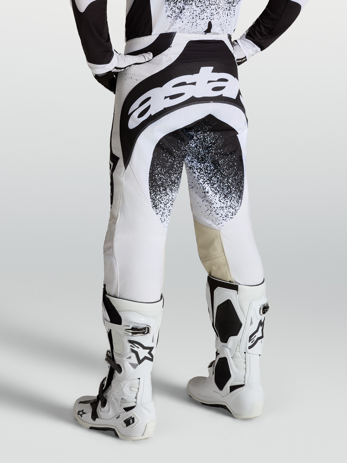 Pantalon Techstar Swan Alpinestars, pantalon de motocross noir et blanc, vue de dos sur mannequin avec bottes blanches, marquage Astar.