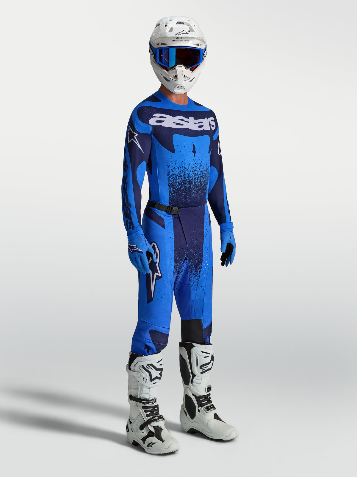 Pantalon Alpinestars Techstar Swan, motocross pour homme, bleu et marine, avec maillot assorti et bottes de course blanches.
