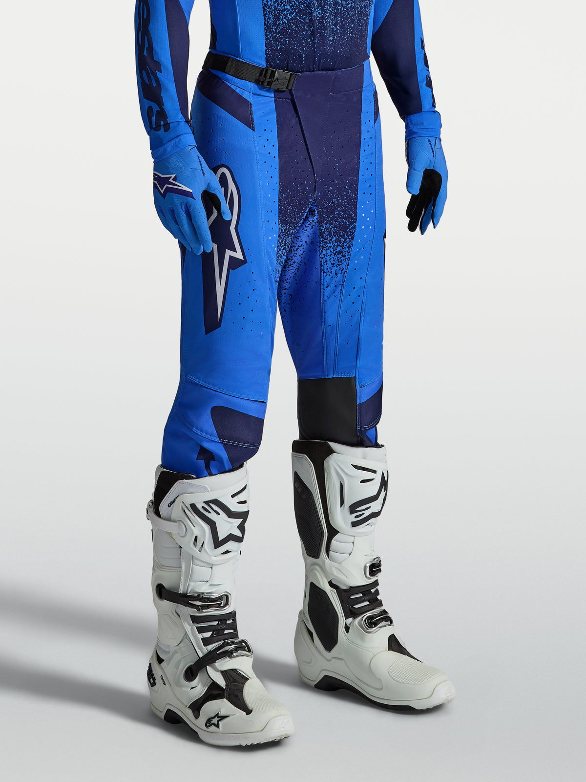 Pantalon Alpinestars Techstar Swan, équipement de motocross pour homme, bleu et bleu marine, construction en poly-tissu 600D renforcé et zones perforées, porté avec des bottes de moto blanches