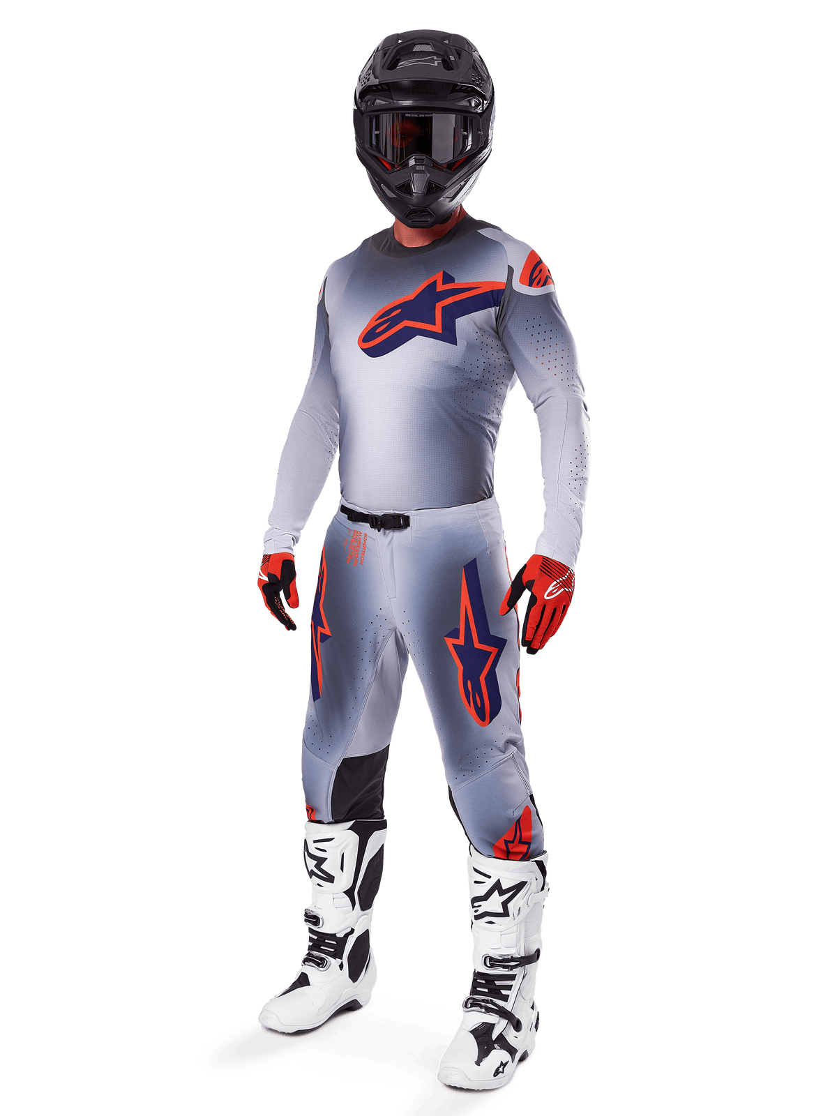 Motocross rider wearing full Alpinestars 2025 Supertech Lipan racing gear set, Gray and Orange Fluo, gray jersey with large orange chest logo, matching pants with orange accents, black helmet, red gloves, and white boots, professional off-road racing outfit