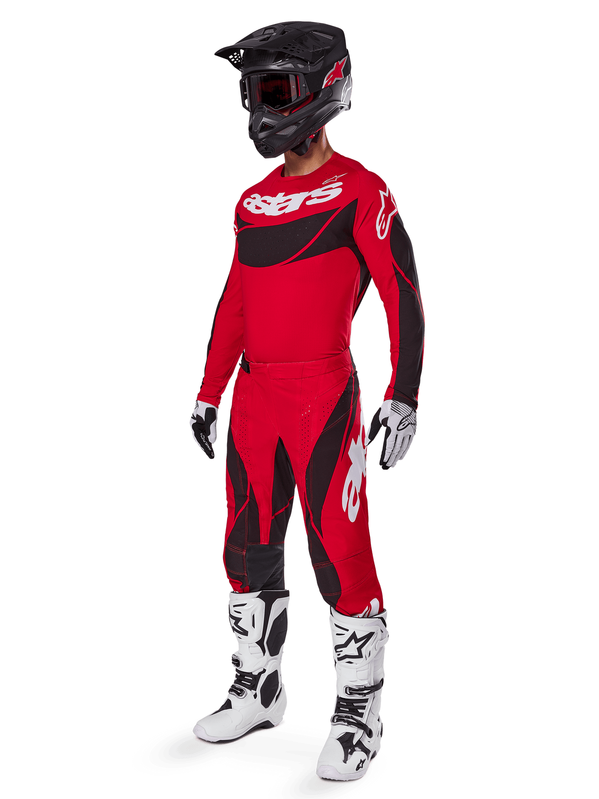 Pilote de motocross portant une tenue de course complète comprenant le pantalon Alpinestars Techstar Dreem 2025 rouge vif et noir, un maillot assorti rouge et noir avec logo blanc, un casque noir et des bottes blanches et noires, tenue coordonnée pour la course tout-terrain
