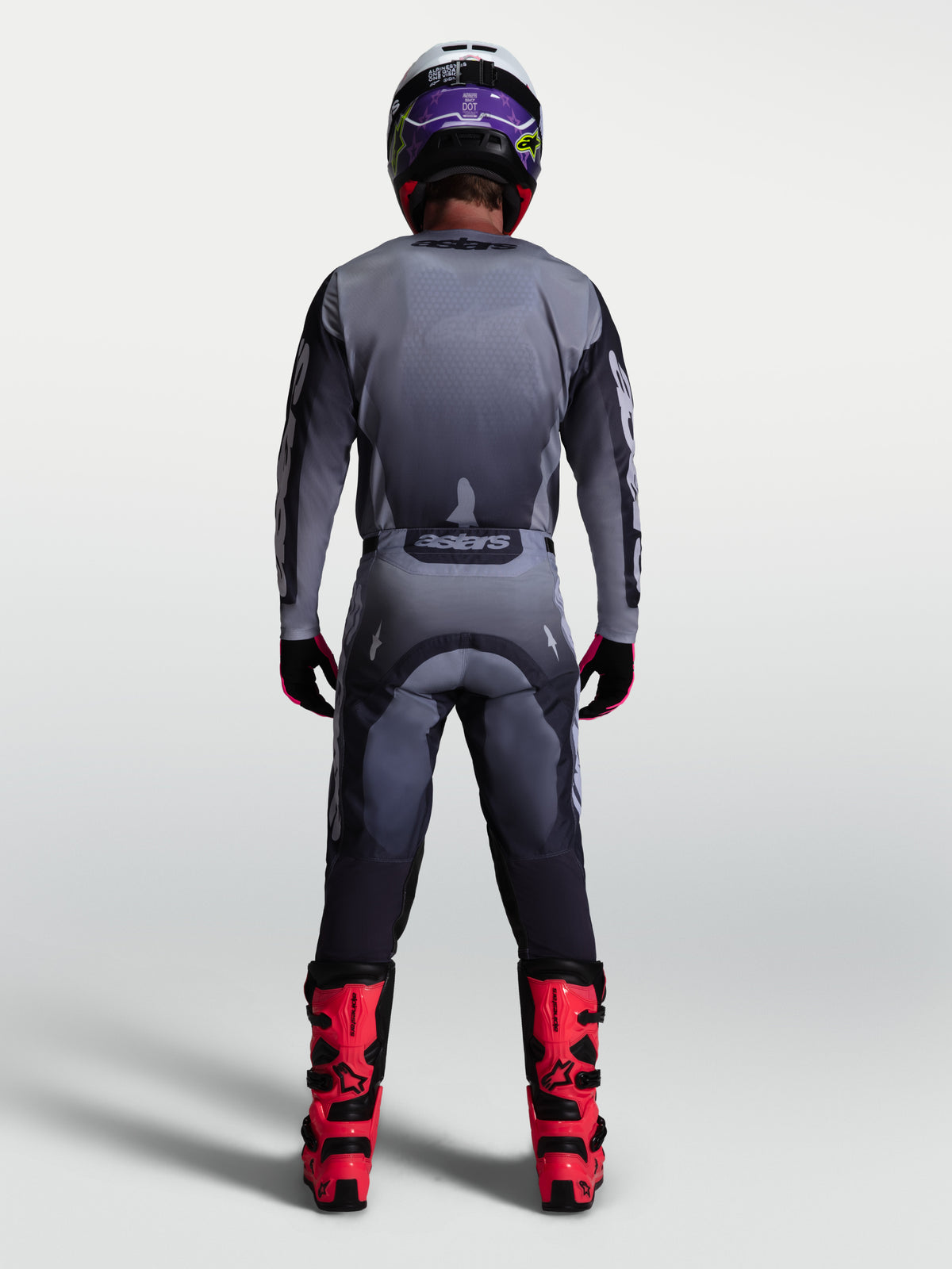 Pantalon Racer Amber Alpinestars, ensemble de motocross pour homme, gris et lilas clair, vue de dos avec bottes de moto rouges, équipement de protection tout-terrain