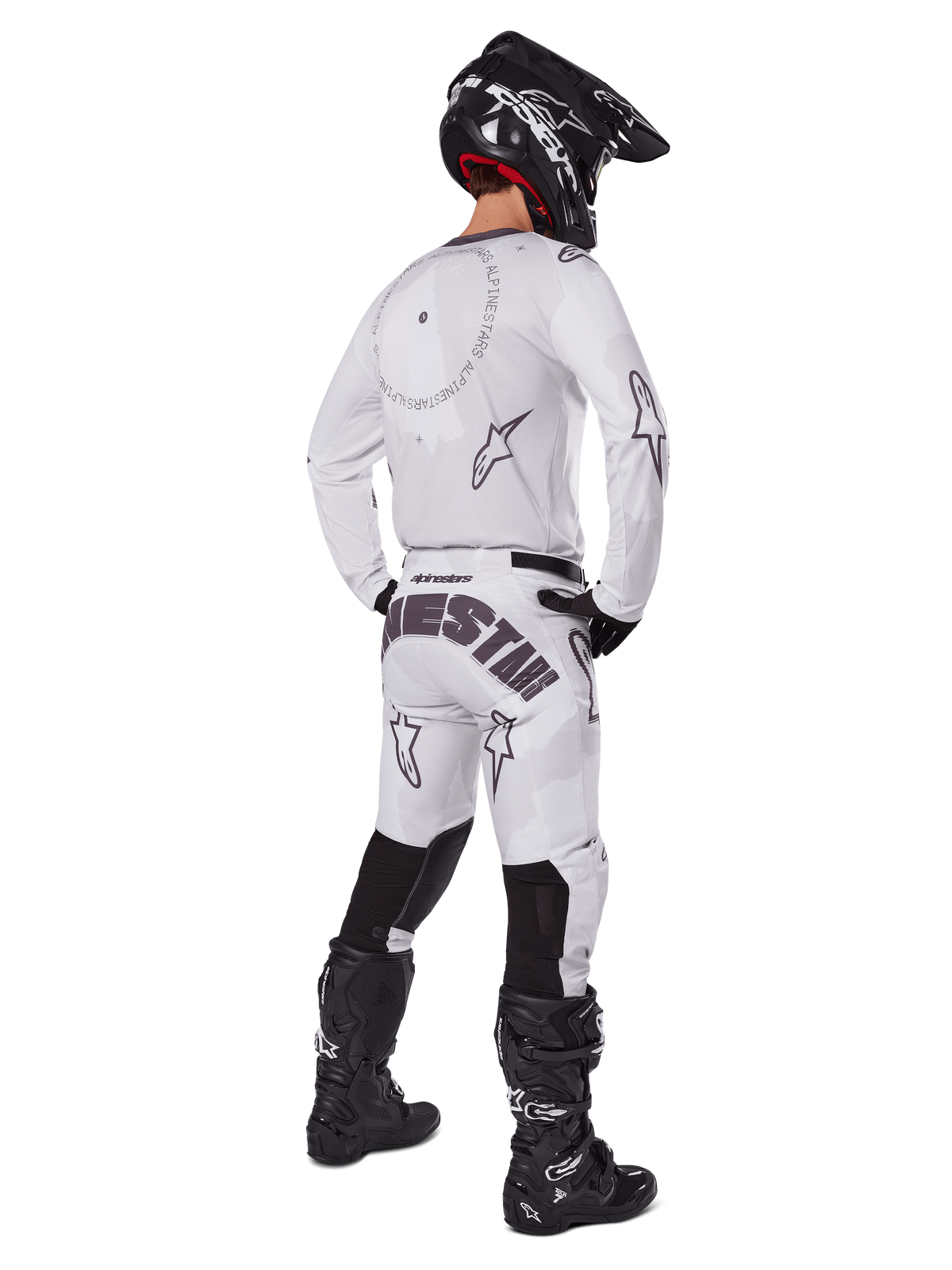 Alpinestars 2025 Racer Hollow Pants, pantalon de motocross, brun camouflage clair et blanc, vue arrière montrant un marquage noir imposant sur l'assise et des logos étoiles, porté avec un maillot assorti, des bottes noires et un casque noir pour un look de course tout-terrain complet