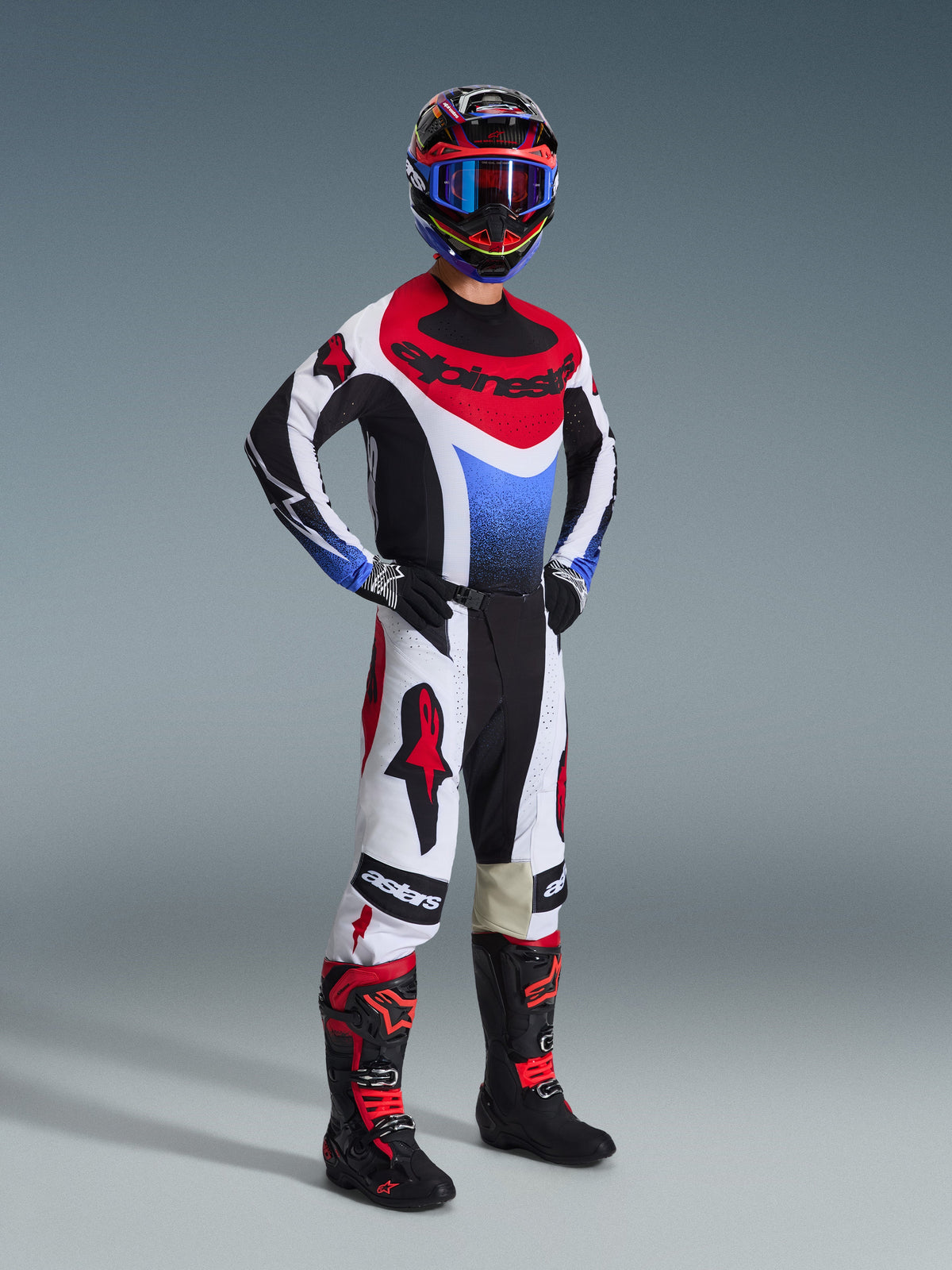 Pantalon Alpinestars Techstar Knif 2026, pantalon de motocross, noir, blanc et rouge, porté par un pilote en tenue de course complète avec maillot et bottes assortis, arborant des logos Alpinestars rouges vifs sur des empiècements blancs et une coupe athlétique axée sur la performance.