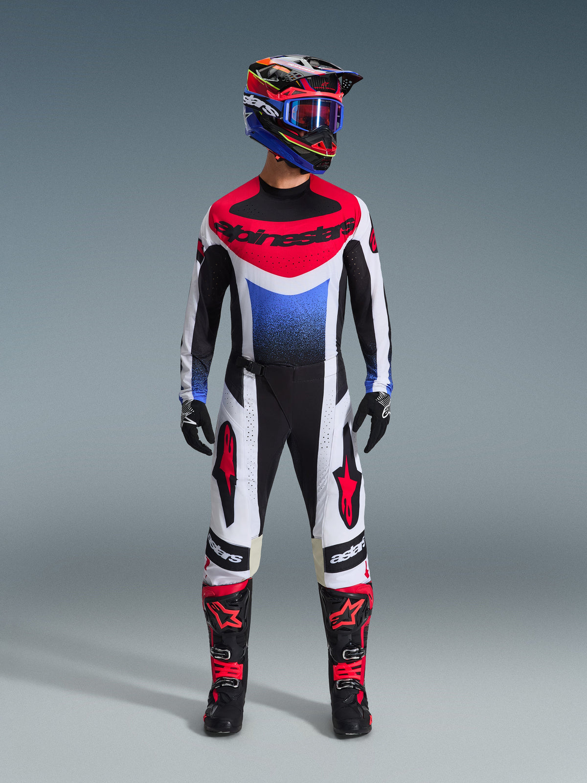 Pantalon Alpinestars Techstar Knif 2026, pantalon de motocross, noir, blanc et rouge, porté avec un maillot et un casque assortis, arborant des logos d'étoiles rouges sur les cuisses et une coupe athlétique pour la course tout-terrain