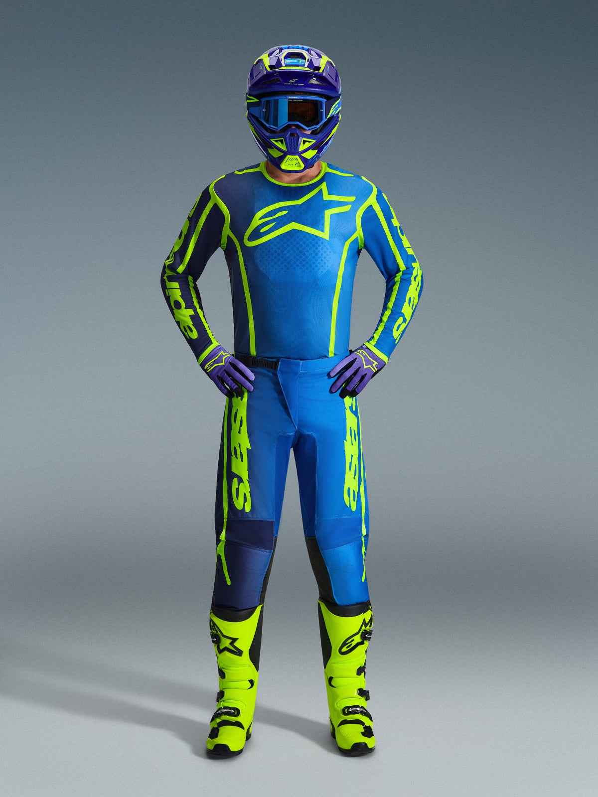 Pantalon Alpinestars Fluid Apex 2026, pantalon de motocross, bleu et jaune fluo, porté par un pilote avec maillot, casque, gants et bottes assortis, arborant un logo Alpinestars jaune vif sur une base bleue, tenue de course tout-terrain coordonnée