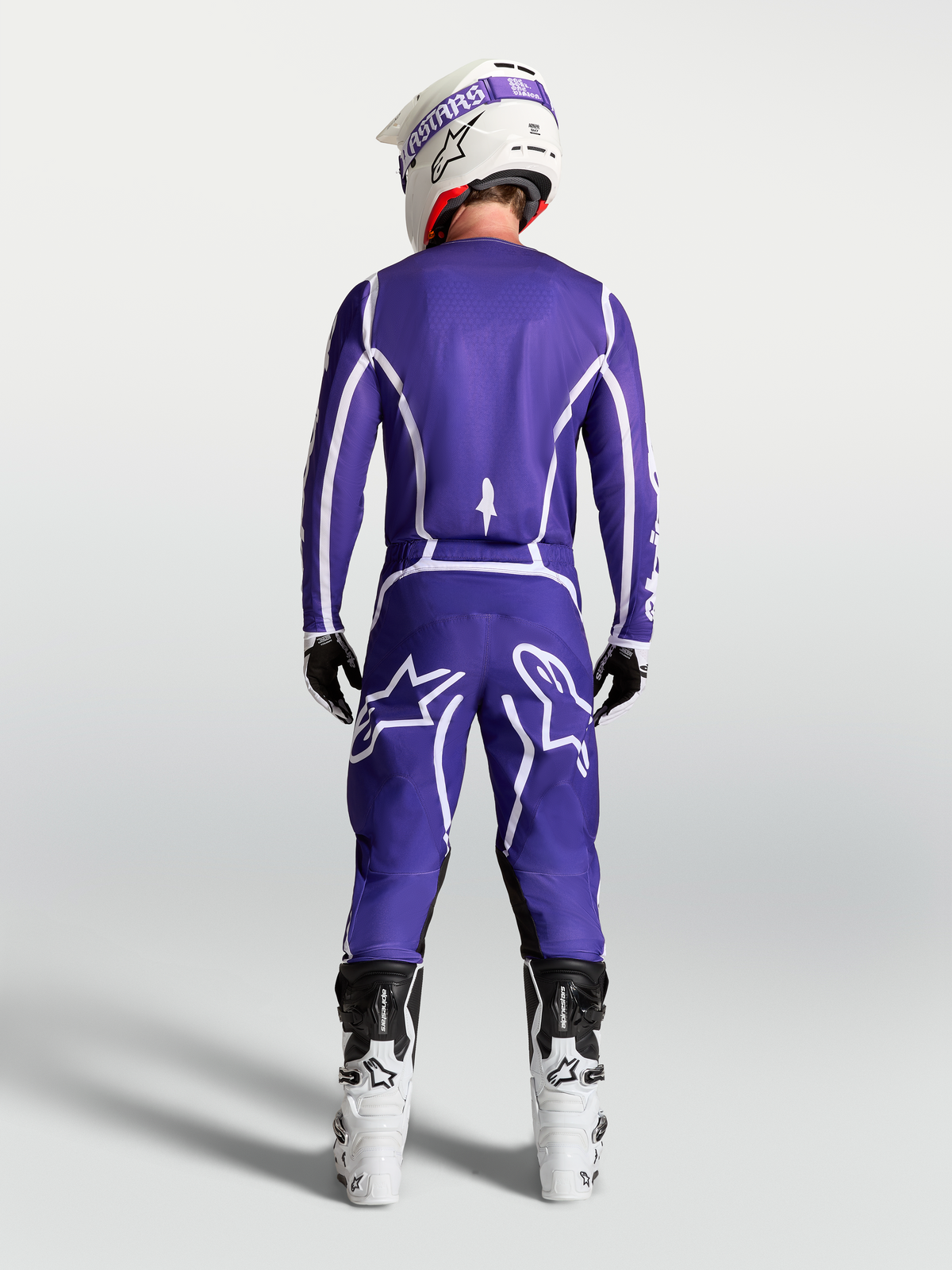 Pantalon Alpinestars Fluid Apex V2 pour homme, bleu foncé et blanc, vue de dos avec bottes de motocross blanches.