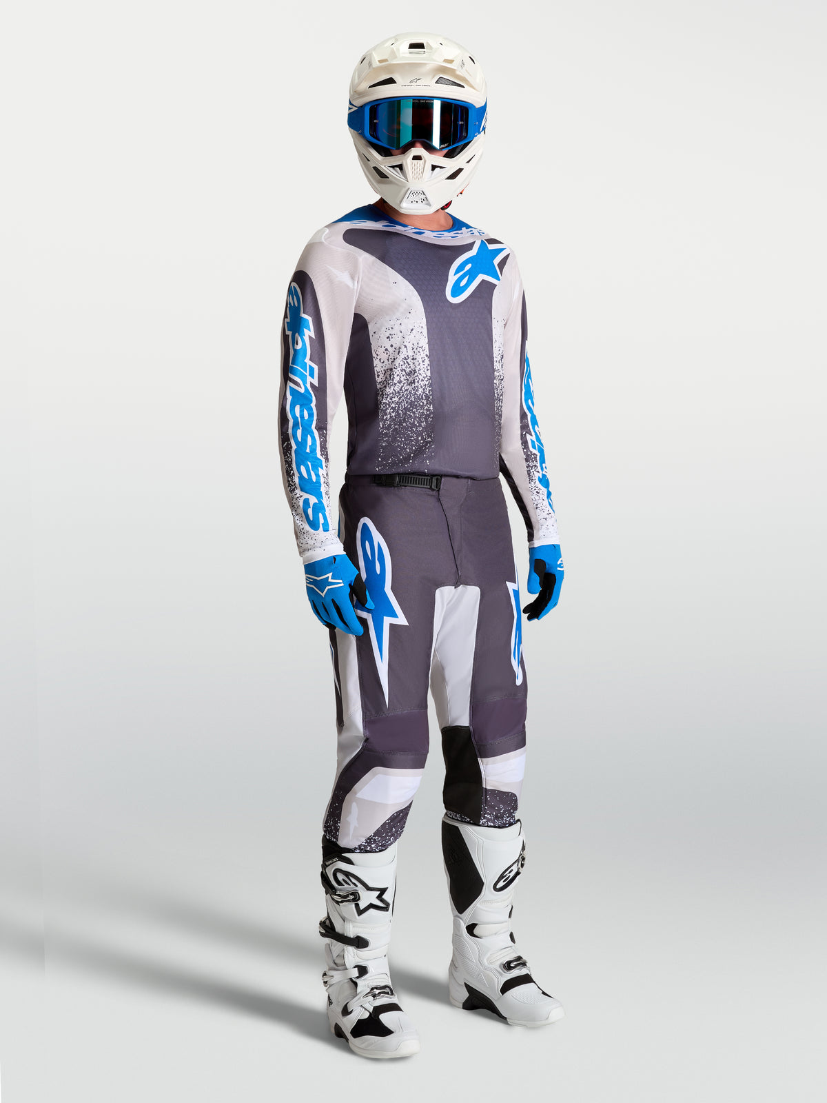 Pantalon Fluid Drag Alpinestars et tenue de motocross, gris, bleu et blanc, design ergonomique 3D pour la performance.