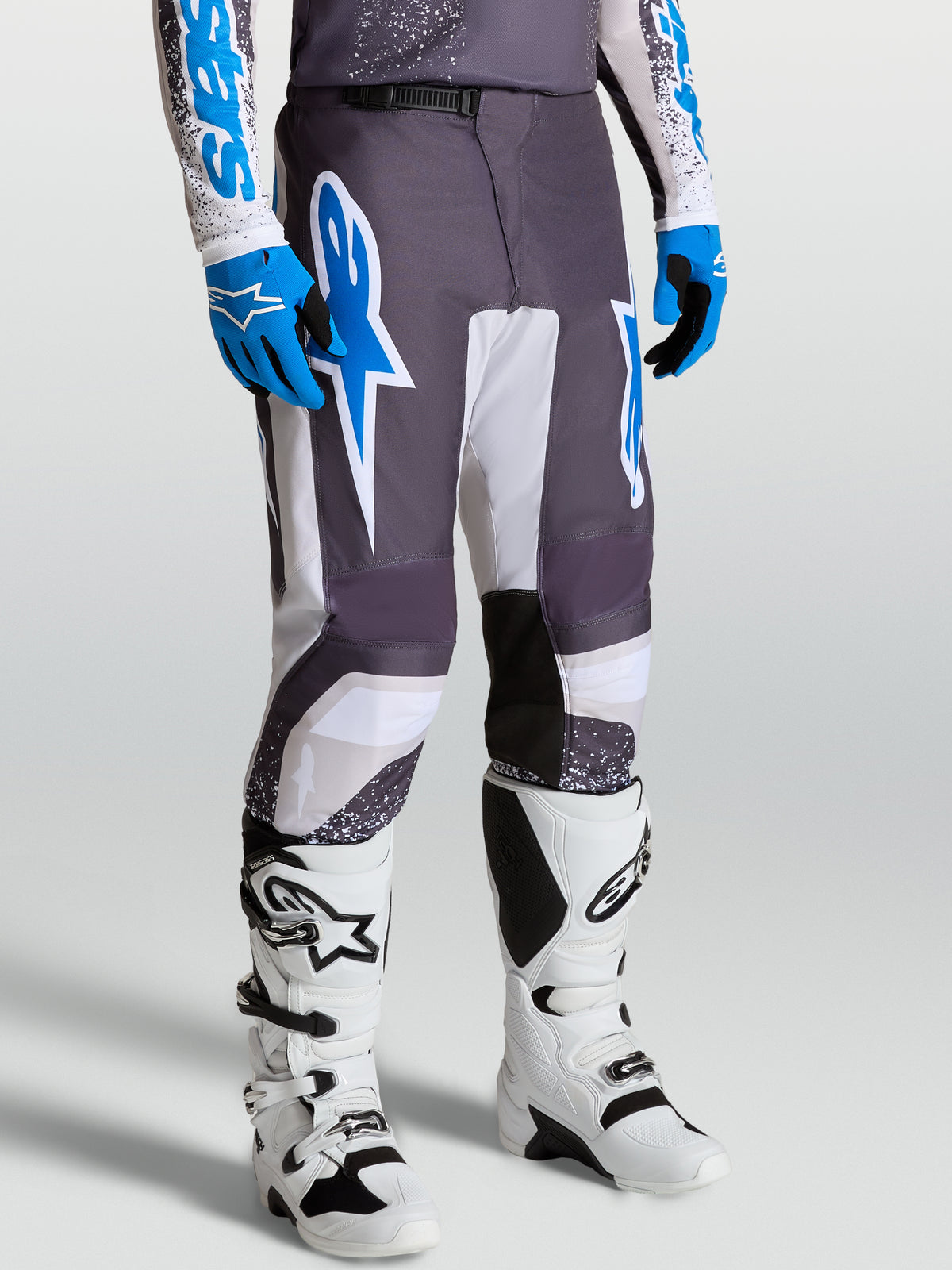 Alpinestars pantalon Fluid Drag, pantalon de motocross homme, gris, bleu et lilas, coupe ergonomique, porté avec des bottes
