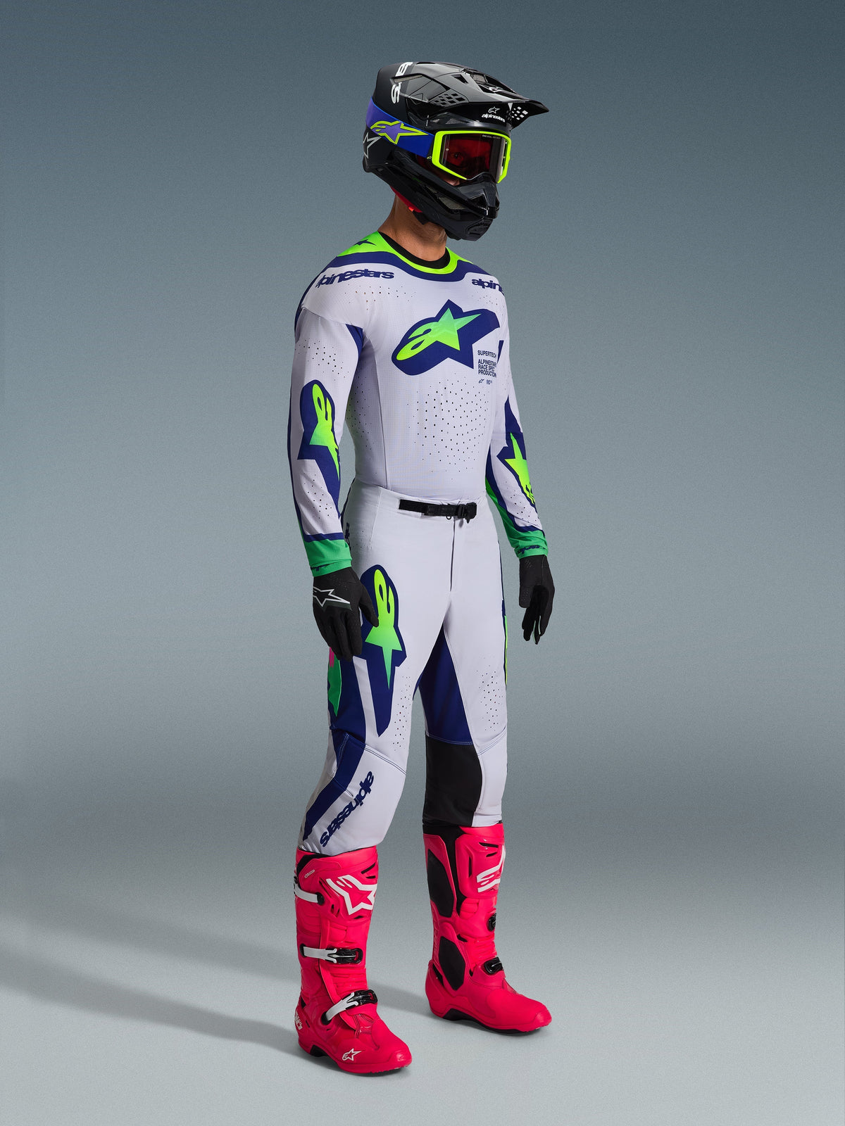 Alpinestars 2026 Supertech Vista Pants and matching jersey, Motocross gear in Light Gray with Yellow Fluo and Blue accents, worn by a rider with a black helmet and vibrant pink boots, featuring bold athletic graphics and professional racing fit