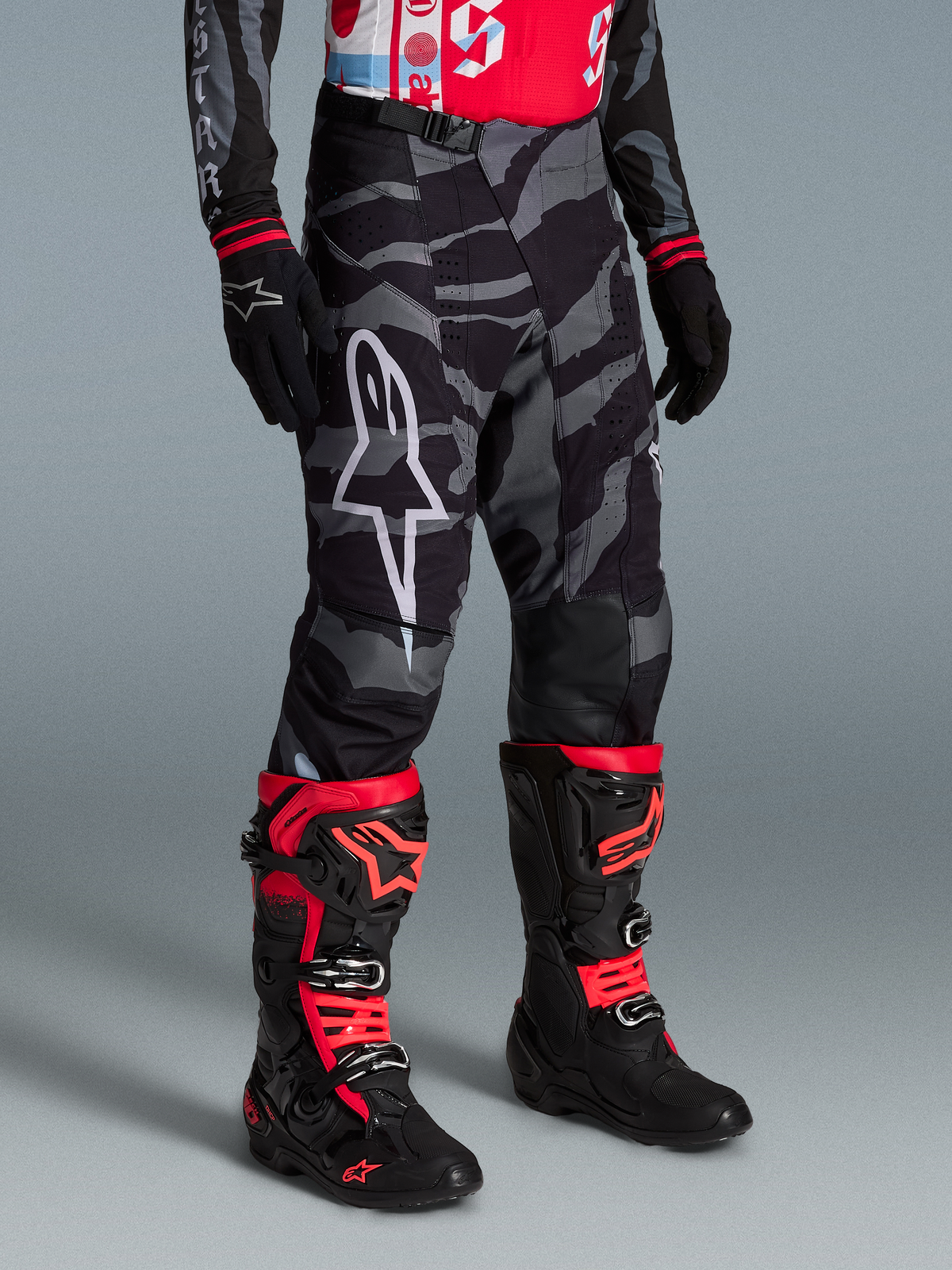 Pantalon Techstar Beast Coast Édition Limitée, camouflage noir et gris, logo étoile blanc, bottes motocross Alpinestars.