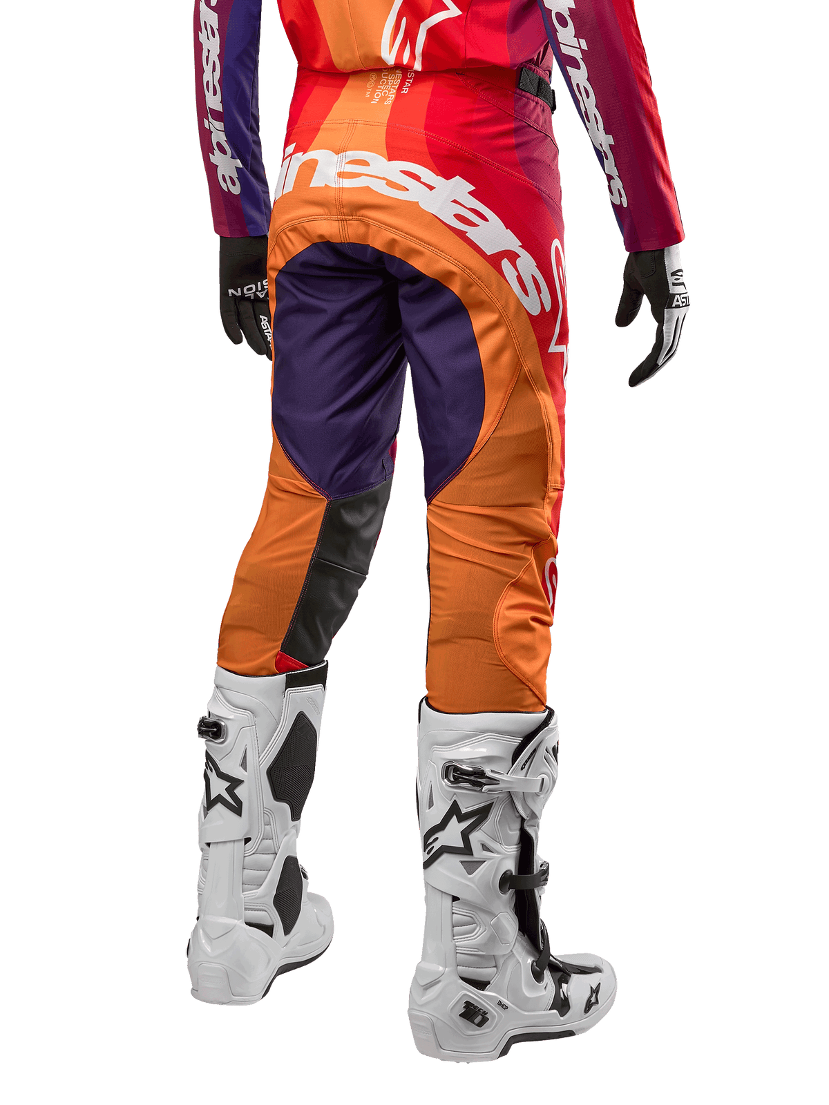 Alpinestars 2024 Techstar Pneuma Pants, pantalon de motocross, violet foncé, orange et bleu profond avec logo blanc à l'arrière, porté avec des bottes blanches et des gants, équipement technique pour motocross.