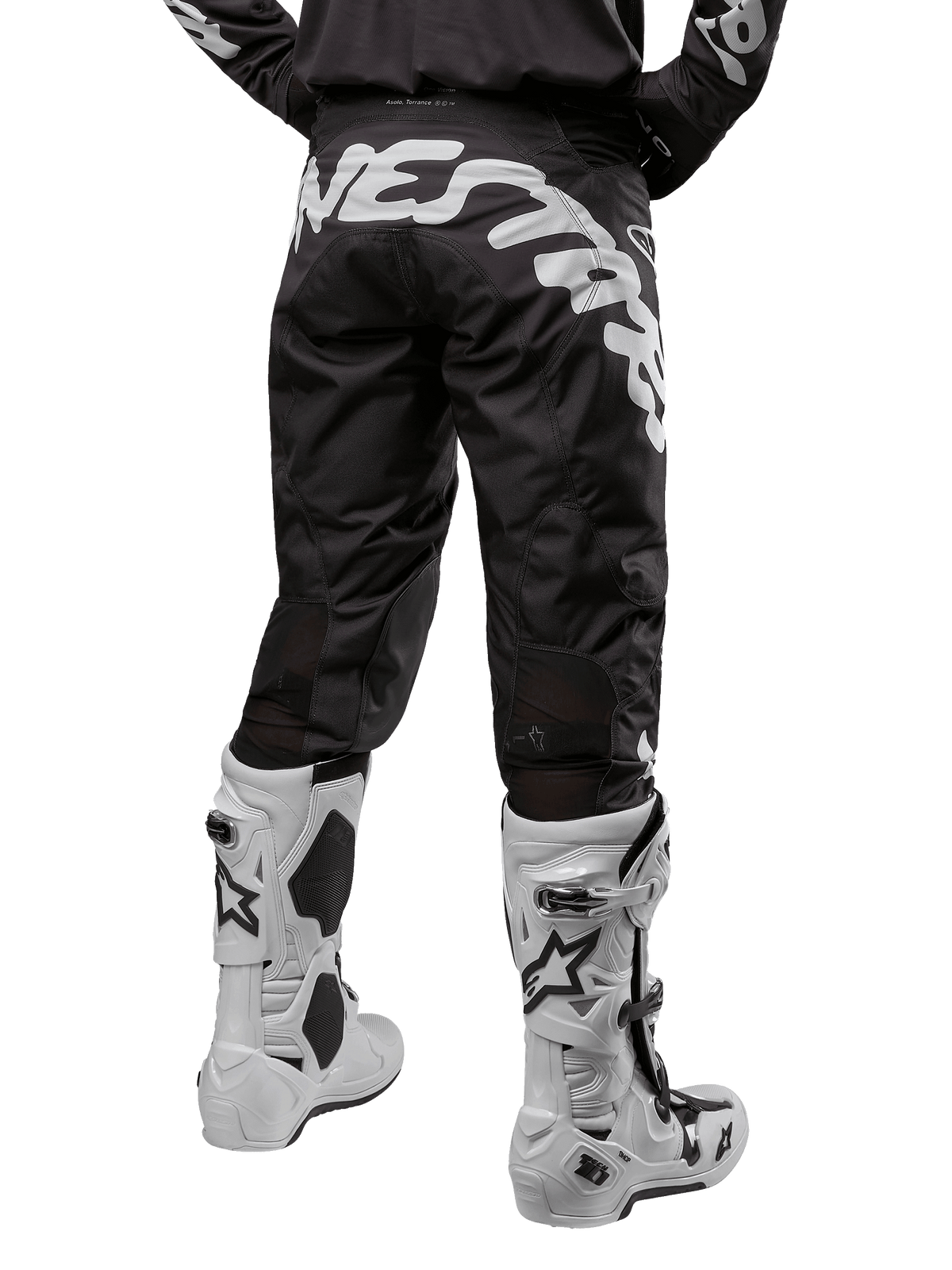 Alpinestars 2024 Racer Hana Pants, pantalon de motocross noir et blanc, vue arrière avec grand logo Alpinestars blanc, construction technique durable, porté avec des bottes de motocross blanches.