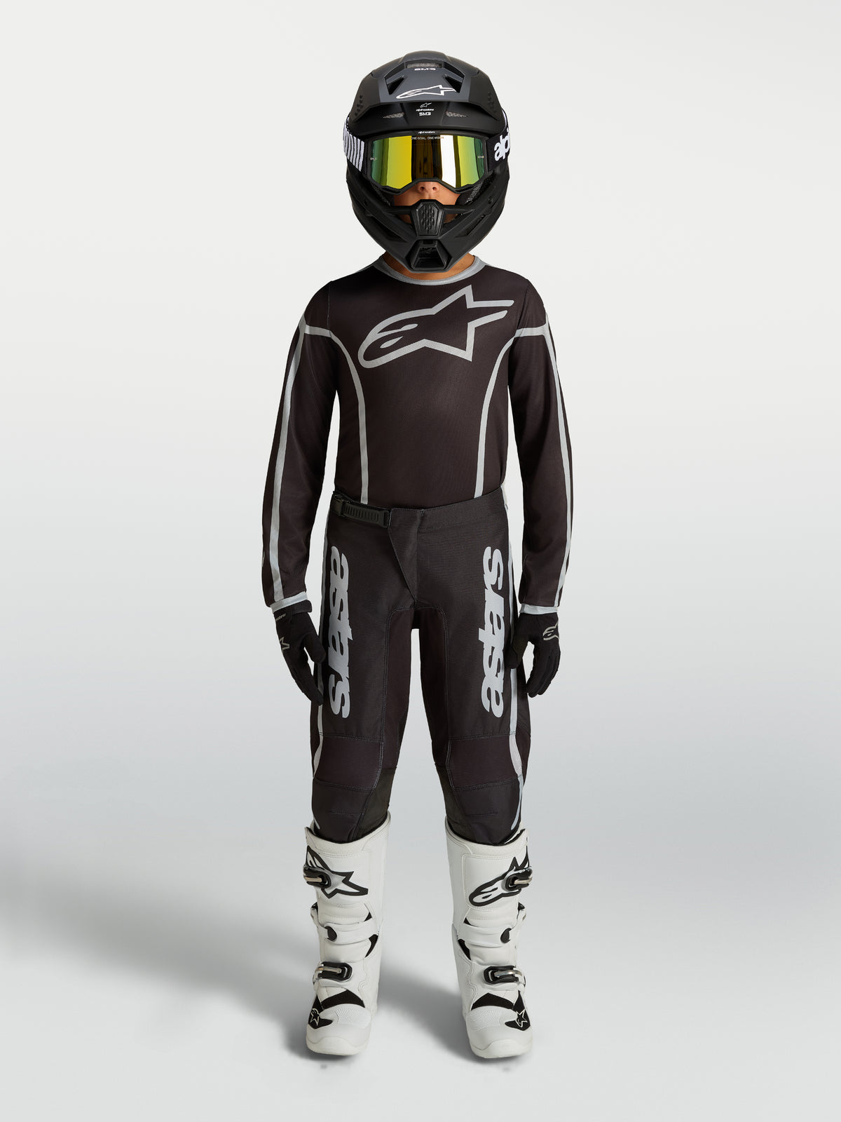 Alpinestars Pantalon Fluid Apex V2 Junior, équipement de motocross noir et argenté pour enfant, avec maillot assorti et bottes blanches, tenue complète de pilotage tout-terrain.