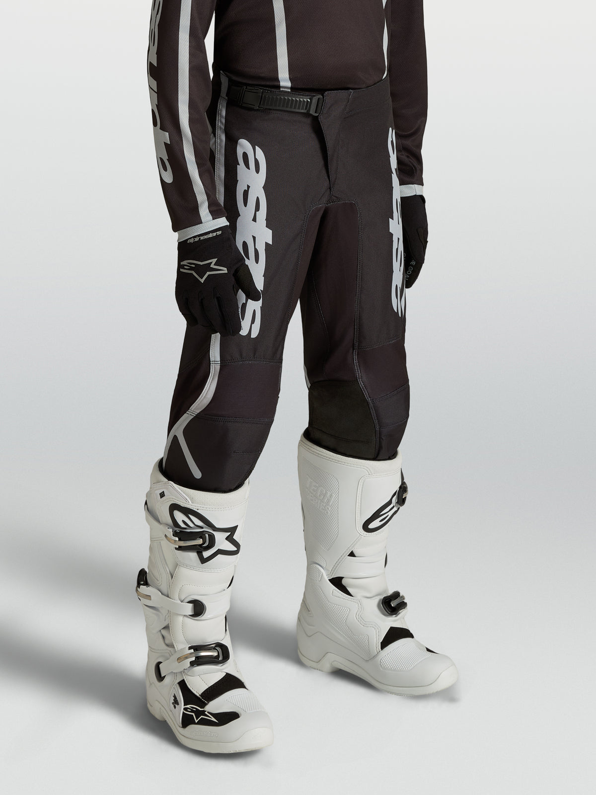 Pantalon Alpinestars Fluid Apex V2 Junior, motocross noir et argenté, coupe ergonomique pré-courbée pour jeunes pilotes.