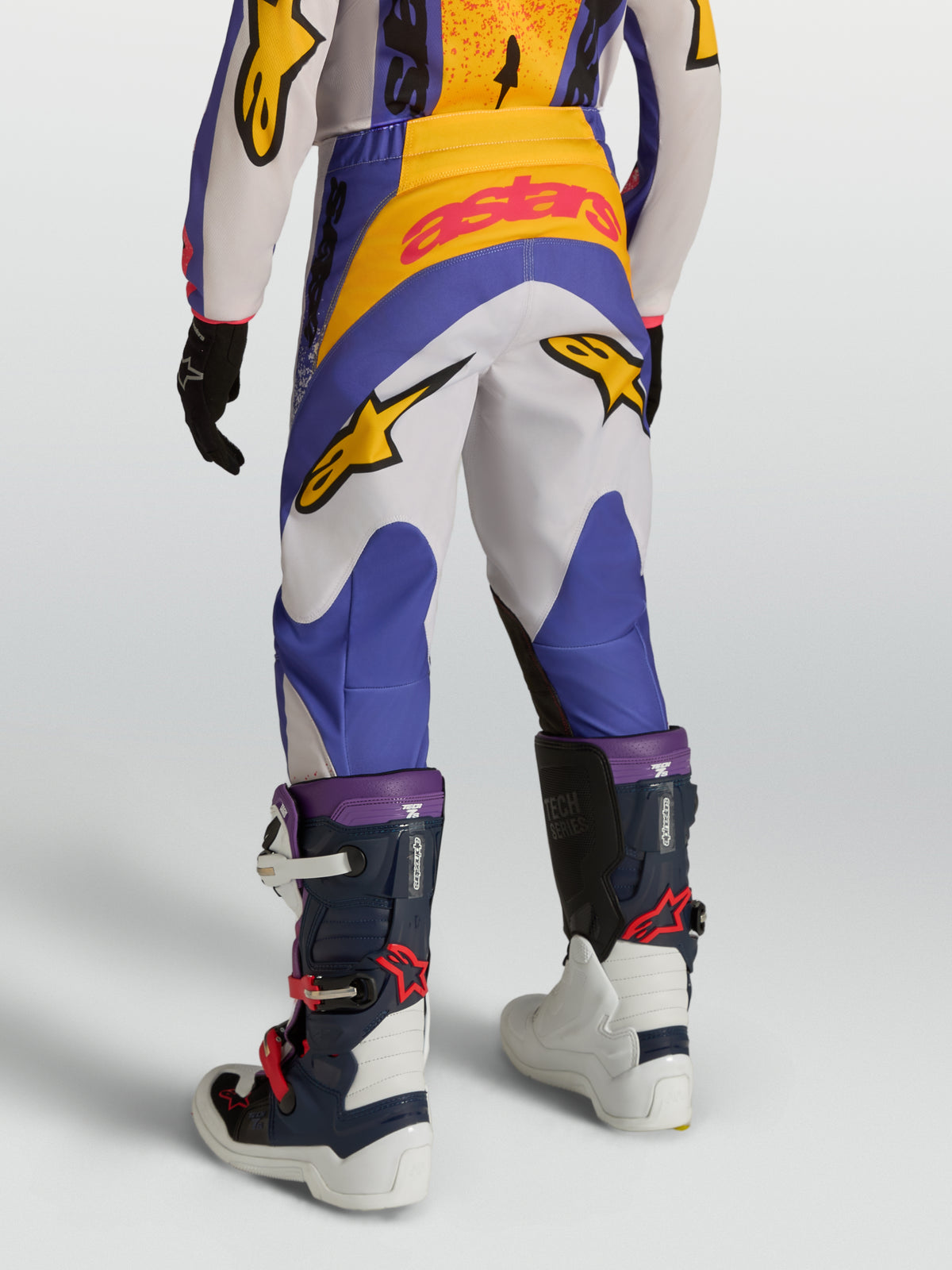 Pantalon Fluid Drag Junior Alpinestars, pantalon de motocross bleu, blanc et jaune, vue de dos porté par un jeune pilote