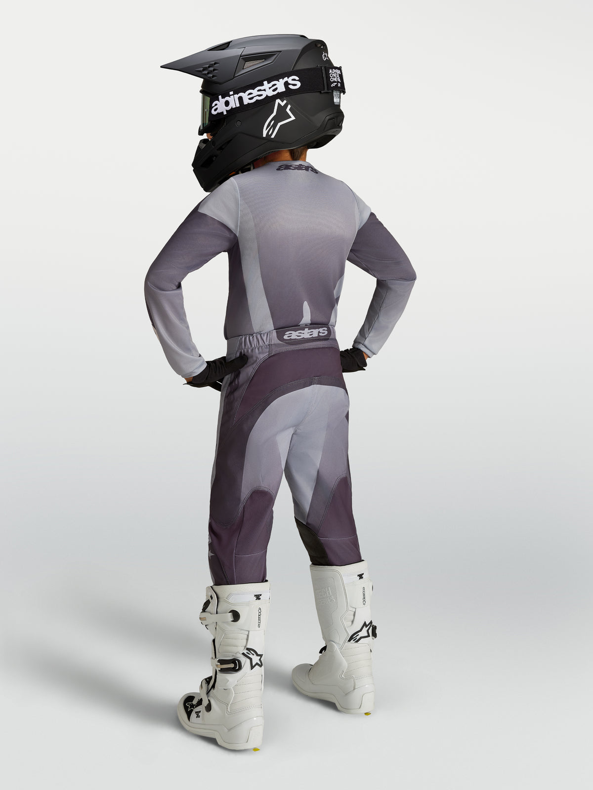 Alpinestars Youth Fluid Amber Pants, gray and charcoal purple sport-fit motocross gear, shown with white racing boots.