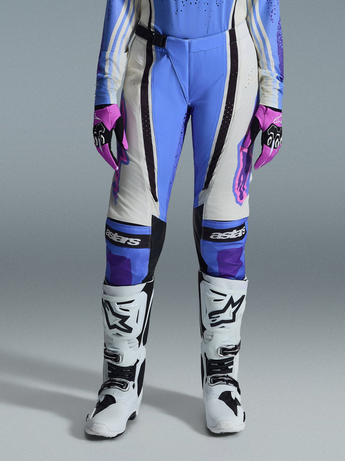 Alpinestars 2026 Woman Stella Techstar Nomur Pants, Motocross Pants, Light Blue, Off White, and Black, worn with white motocross boots and pink and black gloves, featuring 'astars' branding on the knees and a technical multi-panel design for female riders.