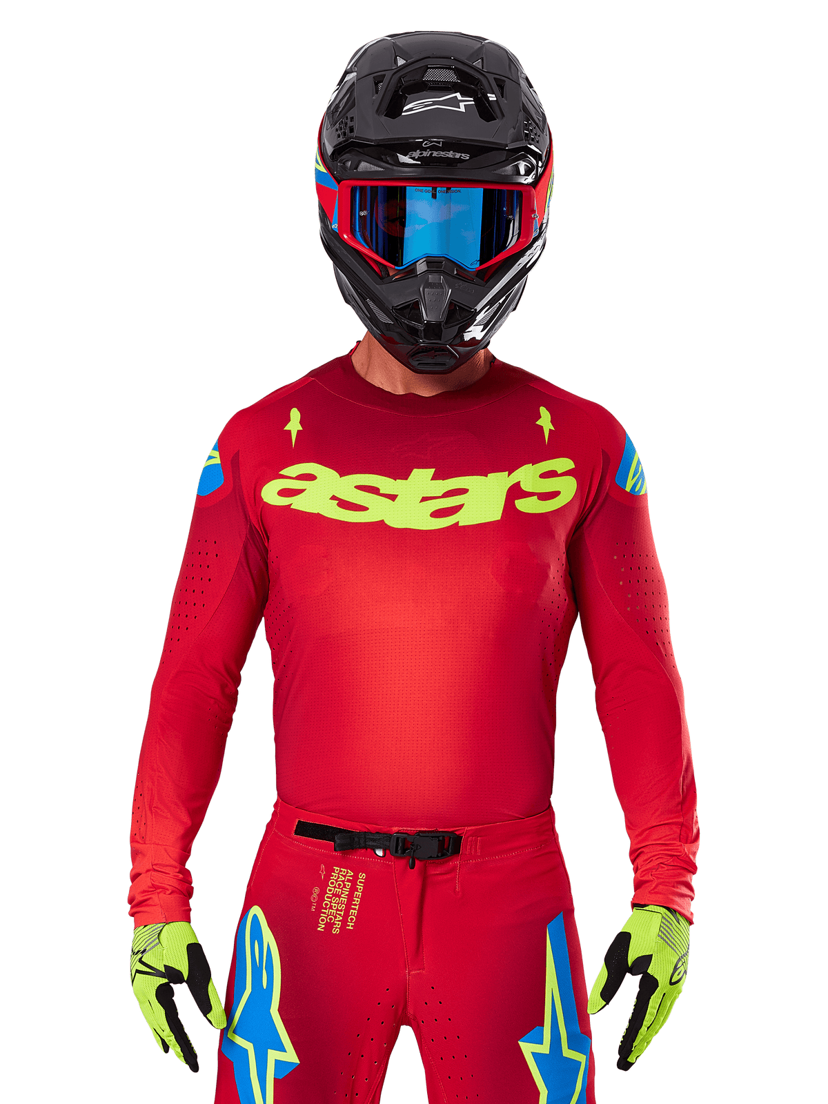 Alpinestars 2025 Supertech Maker Jersey en rouge vif et jaune fluo, avec logo 'astars' jaune sur la poitrine et motifs d'étoiles bleues sur les épaules, porté avec un pantalon assorti, un casque noir, des lunettes bleues et des gants jaunes, équipement de motocross professionnel