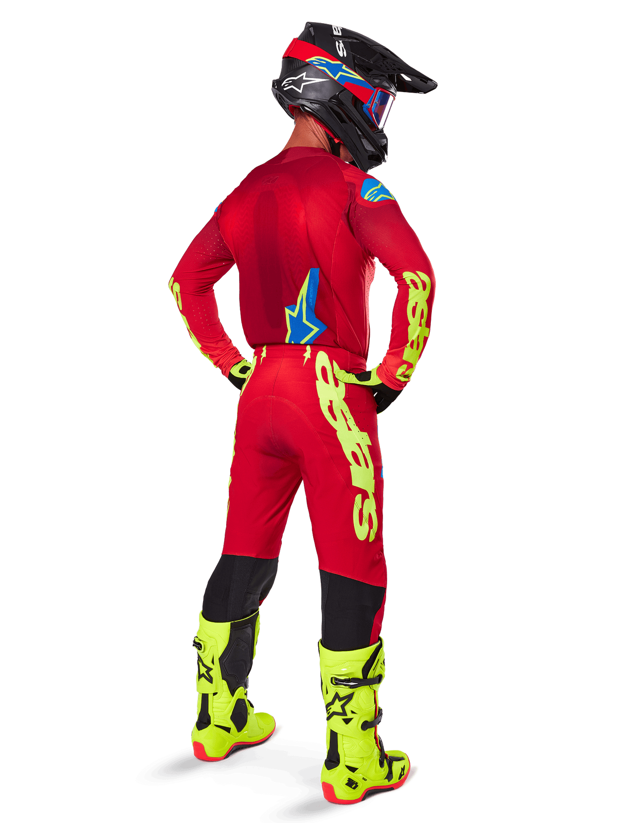 Pilote de motocross vu de dos portant l'ensemble d'équipement Alpinestars 2025 Supertech Maker, maillot rouge vif avec marquage jaune fluo, pantalon rouge assorti avec accents jaunes, casque noir avec détails rouges et bleus, bottes jaune fluo, tenue de course professionnelle coordonnée pour la performance tout-terrain.