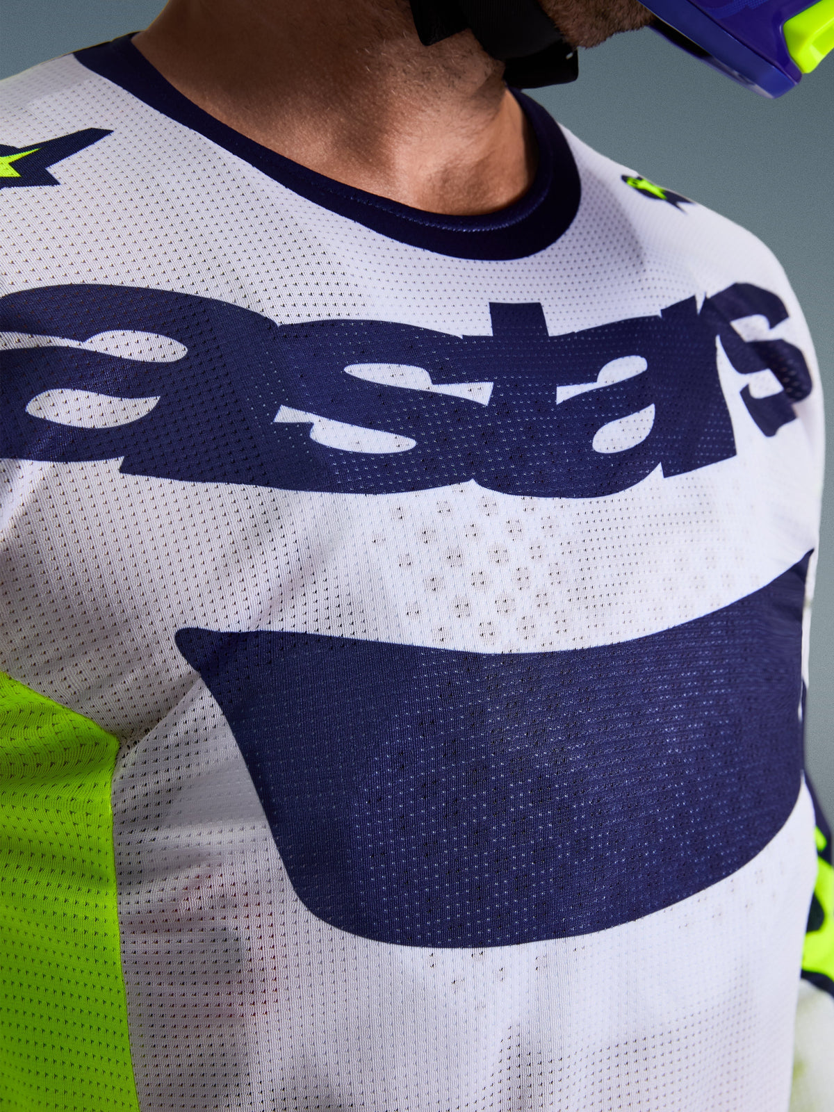 Maillot Alpinestars Racer Air Riway 2026, maillot de motocross, gris clair, jaune fluo et bleu, gros plan sur la poitrine présentant une structure en maille respirante et le logo astars bleu marine, conçu pour le pilotage tout-terrain haute performance.