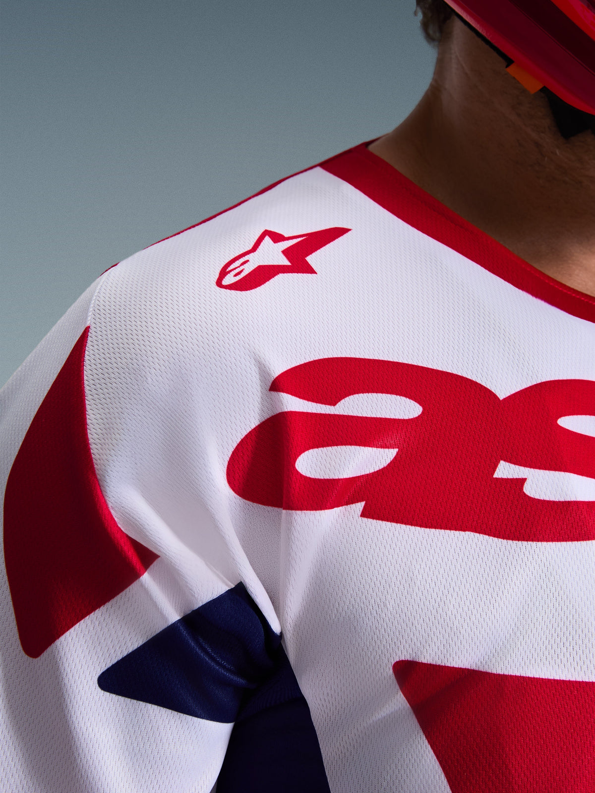 Close-up detail of the Alpinestars 2026 Racer Riway Jersey in White, Blue, and Red, highlighting the breathable mesh polyfabric construction, red Alpinestars logo on the shoulder, and moisture-wicking material for off-road racing.