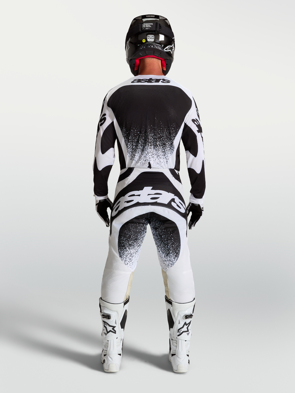 Ensemble et maillot Alpinestars Techstar Swan, tenue de motocross homme noire et blanche avec motifs d'éclaboussures.
