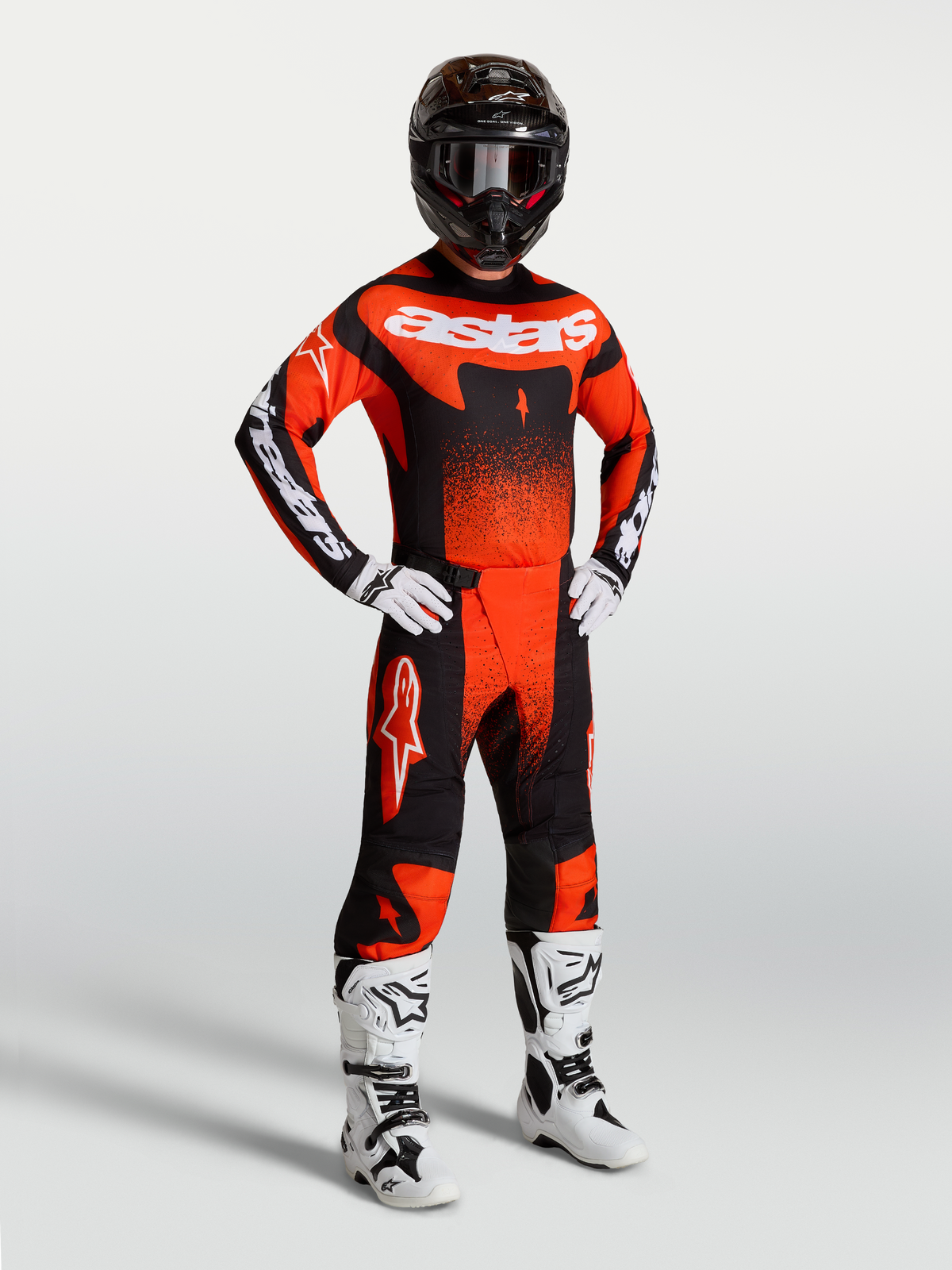 Alpinestars Techstar Swan, ensemble de motocross pour homme, rouge cardinal et noir, porté avec des bottes de moto blanches.
