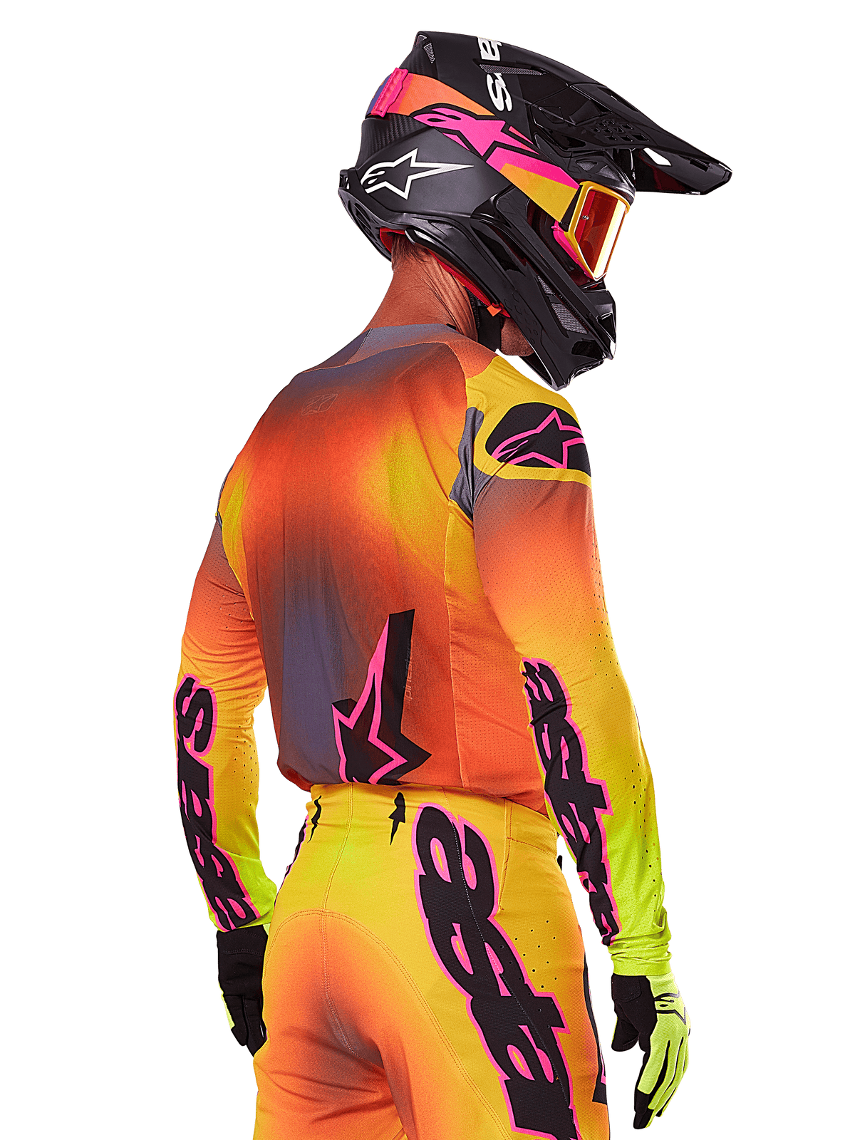 Pilote de motocross vu de trois-quarts arrière portant l'ensemble d'équipement Alpinestars Supertech Lipan 2025, présentant un dégradé jaune, orange et rouge avec des logos noirs et roses, casque noir avec accents roses et lunettes orange, tenue de course tout-terrain professionnelle.