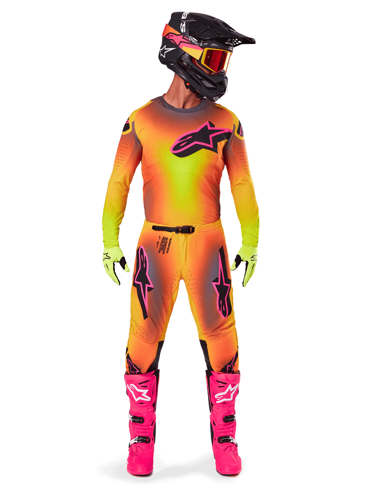 Pilote de motocross portant une tenue de course complète, maillot et pantalon Supertech Lipan 2025 dans un dégradé jaune et orange avec des accents roses, casque noir avec graphismes roses assortis, bottes rose vif et gants vert citron, tenue de course tout-terrain Alpinestars coordonnée.