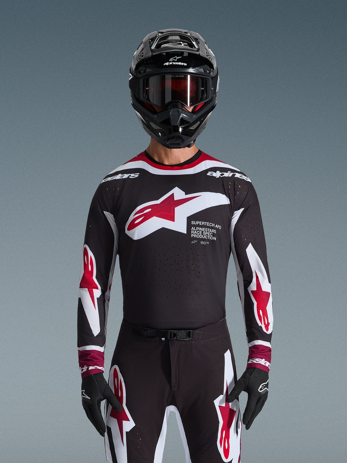 Ensemble d'équipement Alpinestars Supertech AFD Vista 2026, tenue de motocross, maillot noir avec logos rouges et blancs et marquage 'Supertech AFD', pantalon noir assorti avec accents rouges, casque noir avec lunettes rouges, tenue de course professionnelle coordonnée