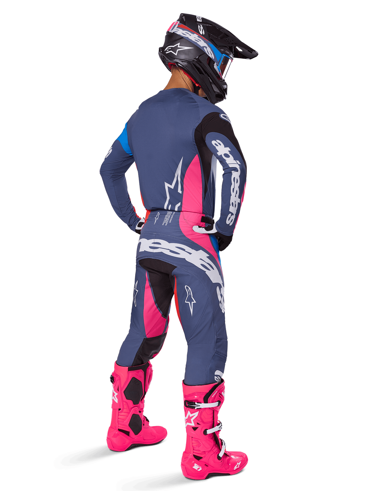 Pilote de motocross vu de dos, portant l'ensemble Alpinestars Techstar Dreem 2025, gris avec accents rose vif et blanc, casque noir et blanc, bottes rose vif, tenue de course complète haute performance