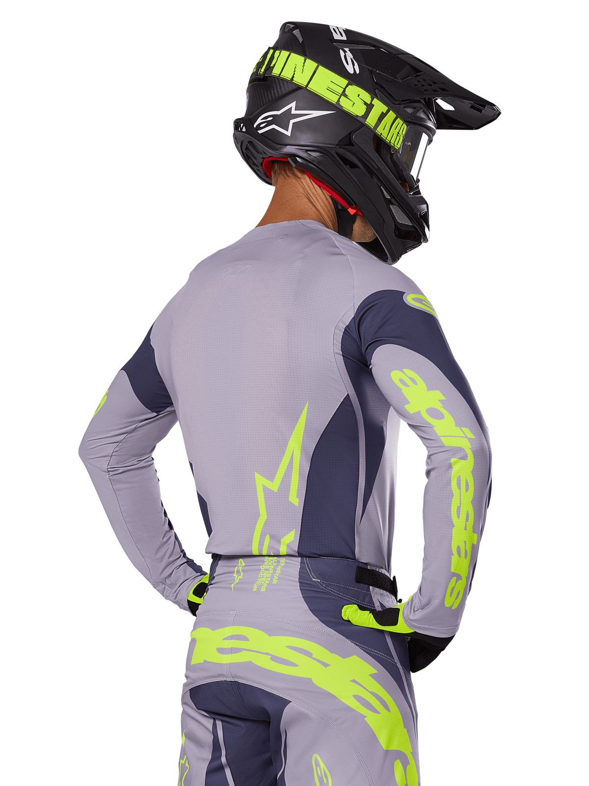Motocross rider from the rear wearing Alpinestars 2025 Techstar Dreem Gear Set, Gray jersey and pants with vibrant neon yellow-green branding, matching black helmet with neon graphics, professional motocross racing outfit