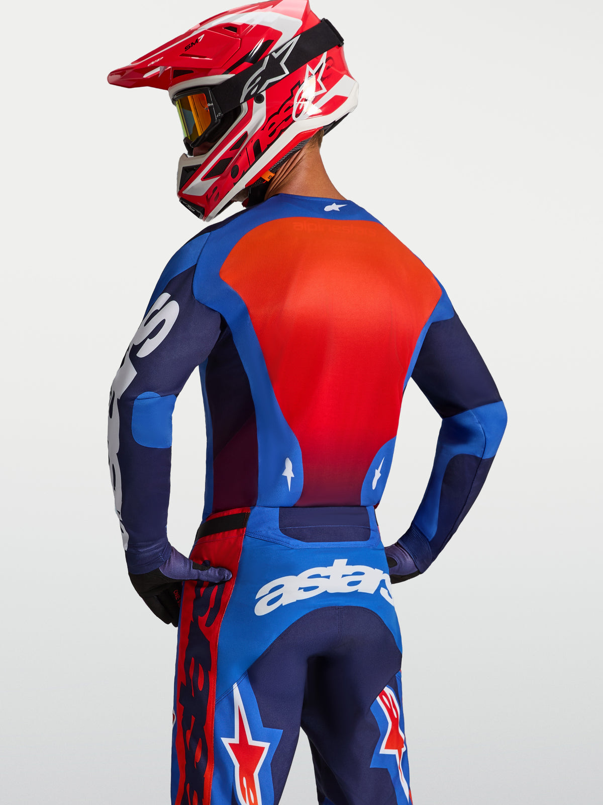 Maillot Racer Hunt d'Alpinestars, maillot de motocross pour homme, bleu et rouge, vue de dos sur un pilote, tissu respirant évacuant l'humidité et coupe de course ergonomique