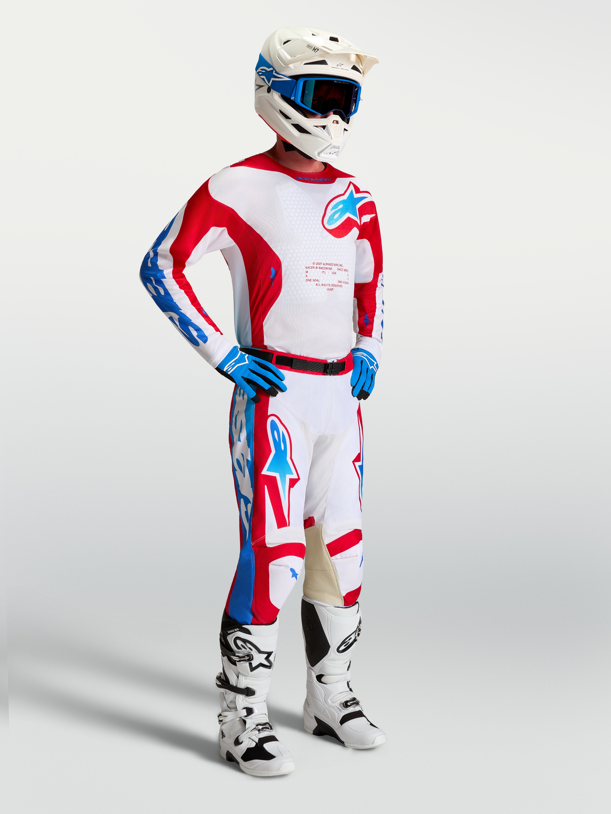 Alpinestars Maillot Racer Hunt, maillot de motocross pour homme, blanc, rouge et bleu, porté par un pilote avec casque et bottes assortis, en poly-tissu léger évacuant l'humidité pour le tout-terrain