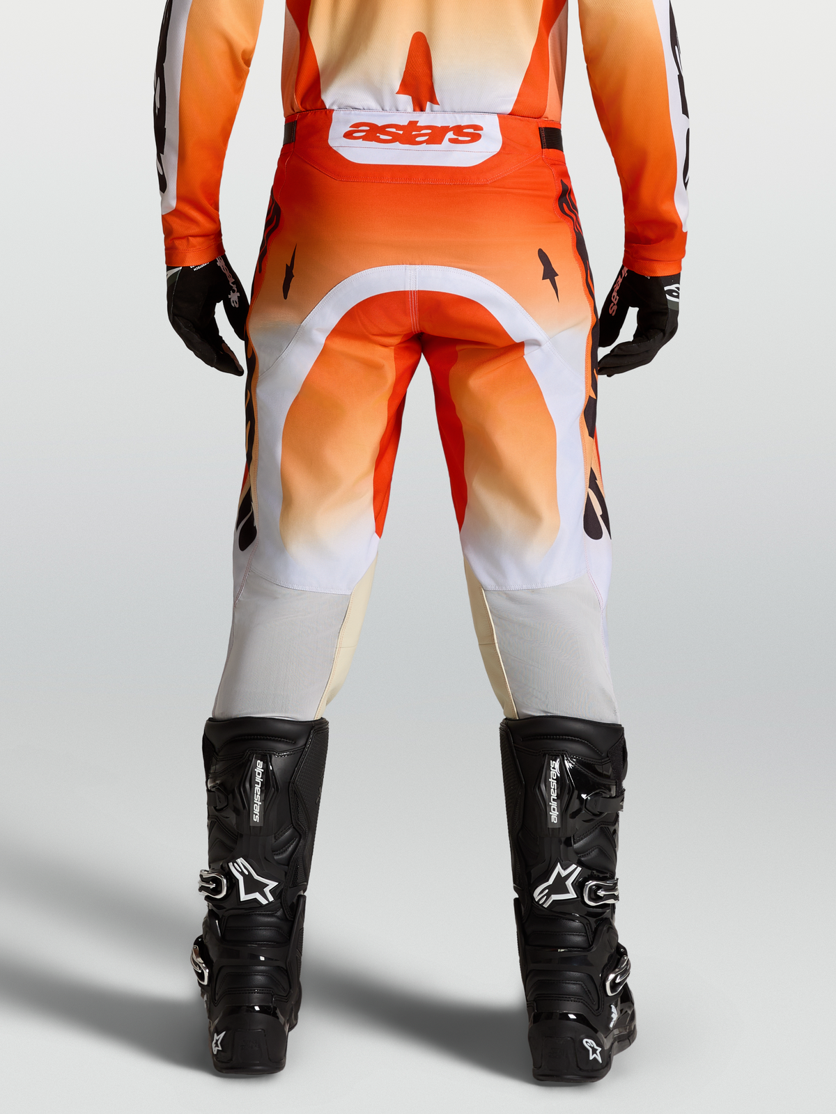 Pantalon Racer Amber Alpinestars, pantalon de motocross orange et blanc, vu de dos sur un mannequin avec des bottes noires