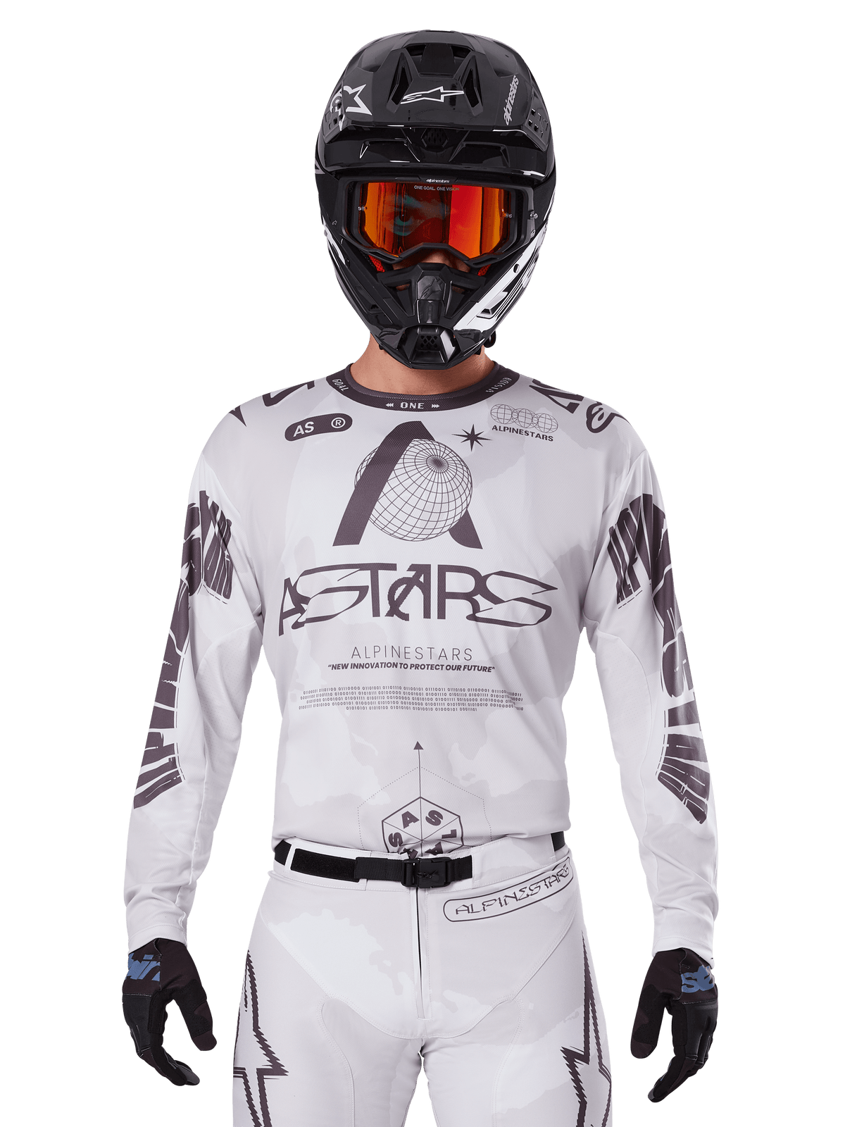 Maillot Alpinestars Racer Hollow 2025, maillot de motocross blanc et noir, porté avec un pantalon de motocross blanc assorti et un casque noir avec des lunettes orange, doté de logos Alpinestars imposants et de graphismes de globe, équipement de course tout-terrain professionnel