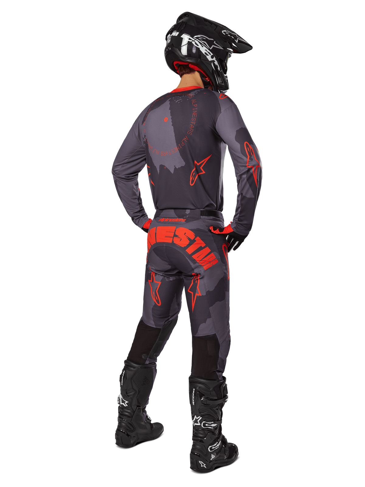 Motocross rider from a rear view wearing the Alpinestars 2025 Racer Hollow Jersey in Gray Camo Orange Fluo, matching camo pants with orange Alpinestars text, black helmet, and black boots, coordinated gear set for off-road riding