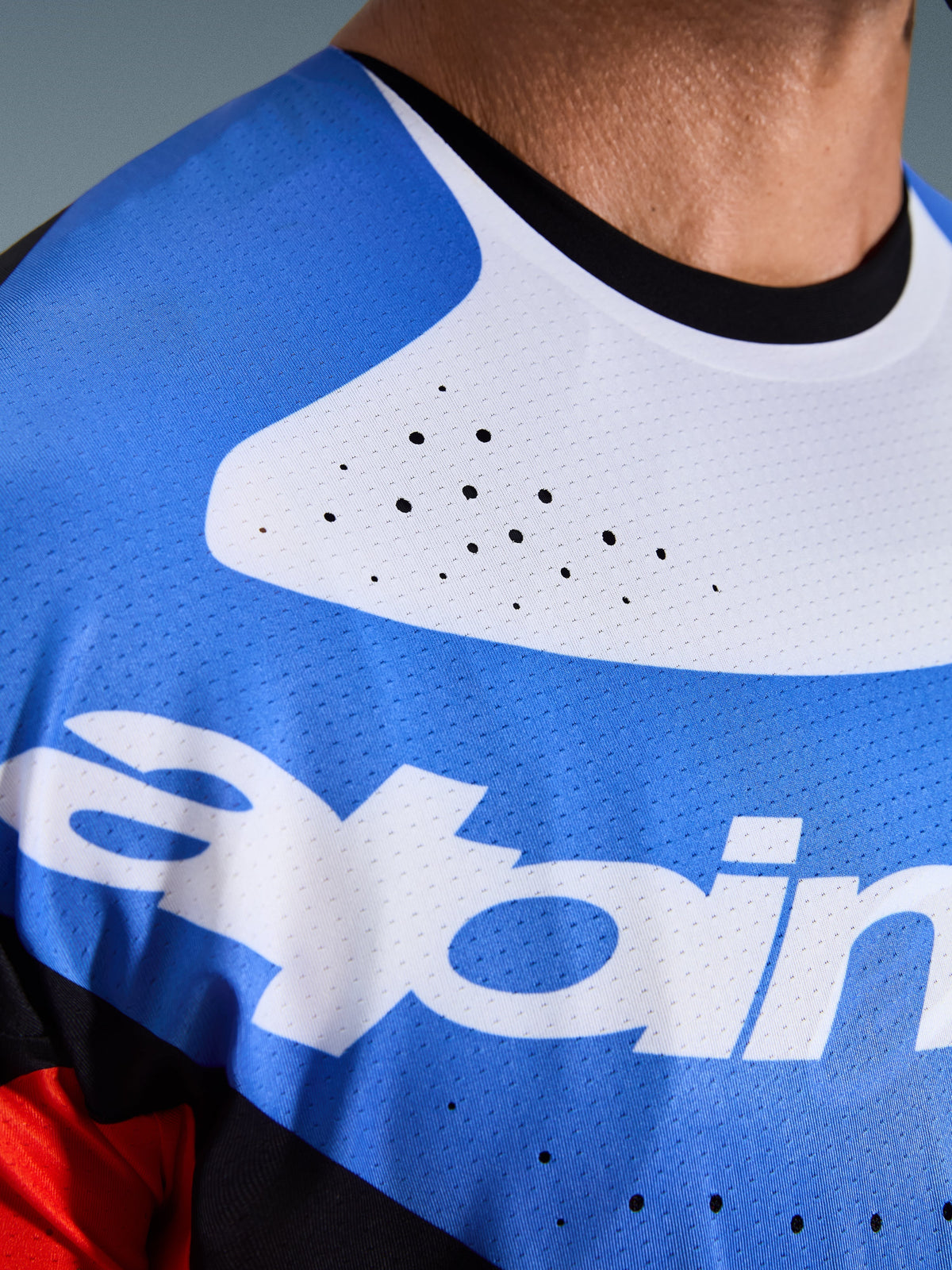Maillot Alpinestars 2026 Techstar Knif, maillot de motocross, gros plan sur la poitrine et le cou, bleu et blanc avec col noir, perforations de ventilation découpées au laser, tissu mesh respirant avec logo Alpinestars.