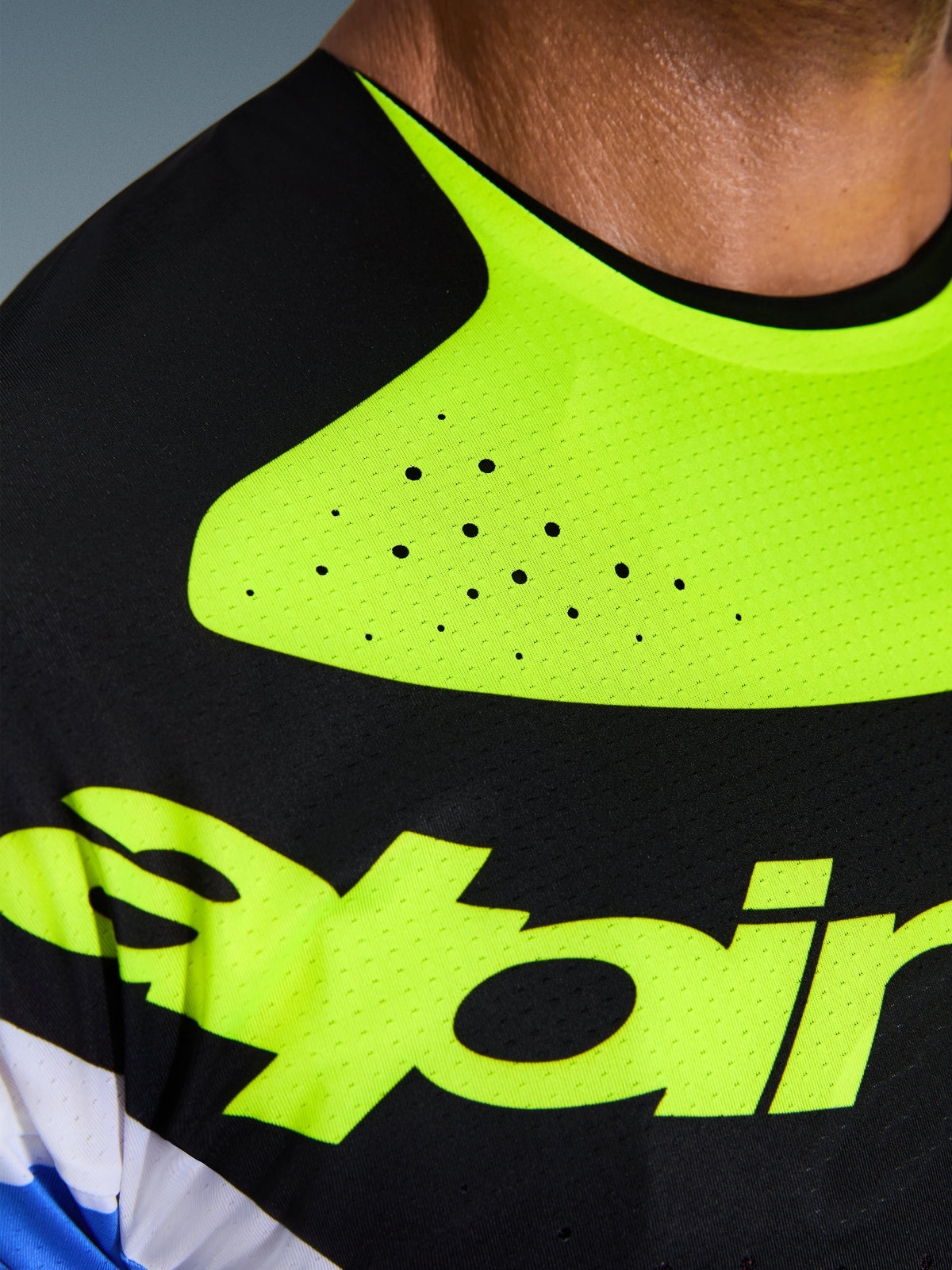 Close-up of the Alpinestars 2026 Techstar Knif Jersey, Black and Yellow Fluo, highlighting laser-cut perforations for ventilation, seamless bonded collar, and technical moisture-wicking fabric with yellow branding.