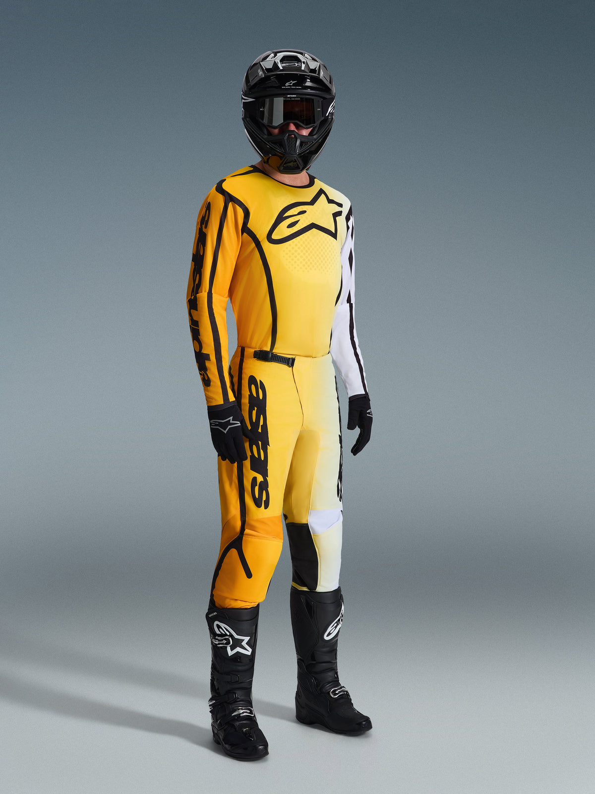 Alpinestars 2026 Fluid Apex Gear Set, Motocross rider wearing yellow, white, and black racing gear, jersey with large chest logo and white sleeve, matching pants with bold branding, black helmet, gloves, and boots, coordinated outfit for off-road racing