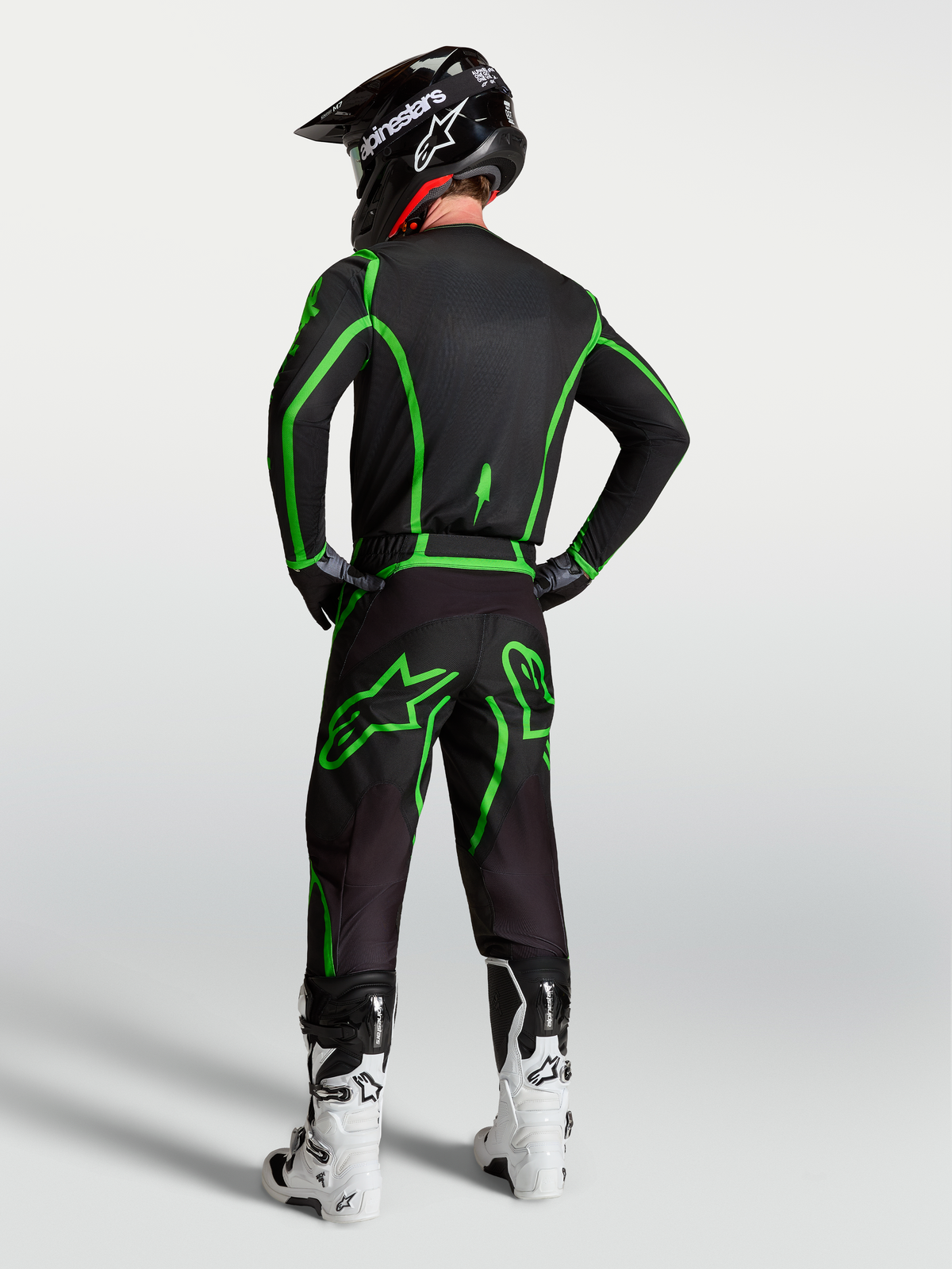 Maillot Fluid Apex V2 d'Alpinestars, équipement de motocross pour homme, noir et vert fluo, vue de dos sur mannequin avec pantalon assorti.