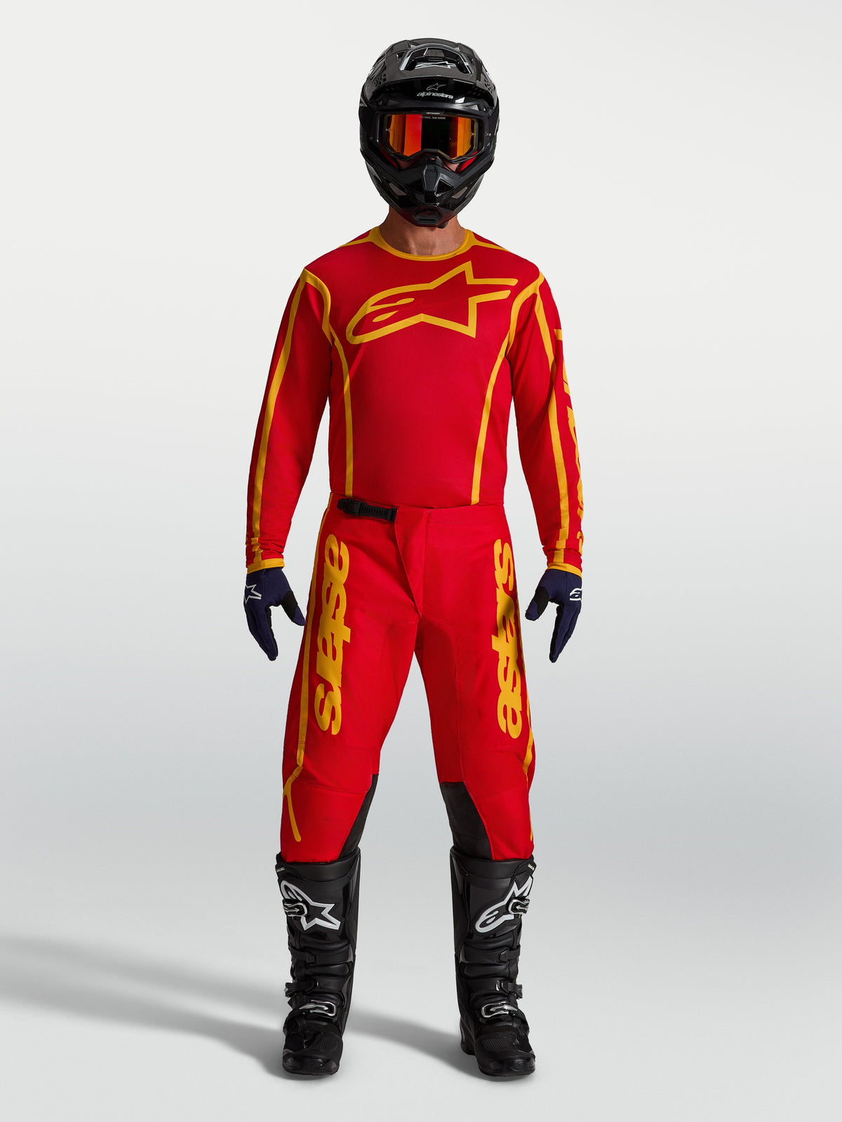 Alpinestars maillot Fluid Apex V2 et Fluid Apex V2 Gear Set, équipement de motocross pour homme, rouge et doré, tissu respirant, porté par un mannequin avec un kit complet.
